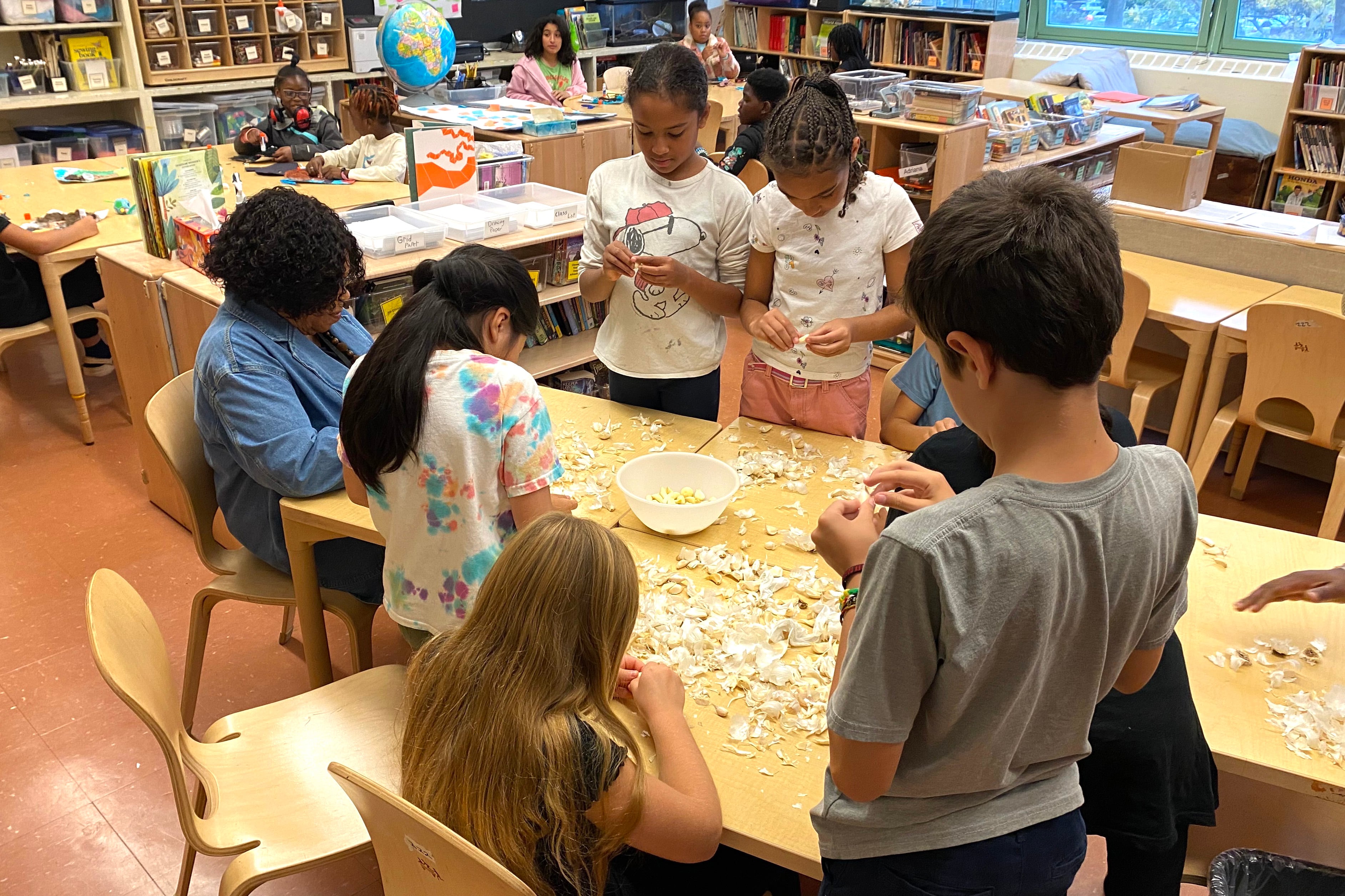 Students and a teacher work at a table in a classroom.