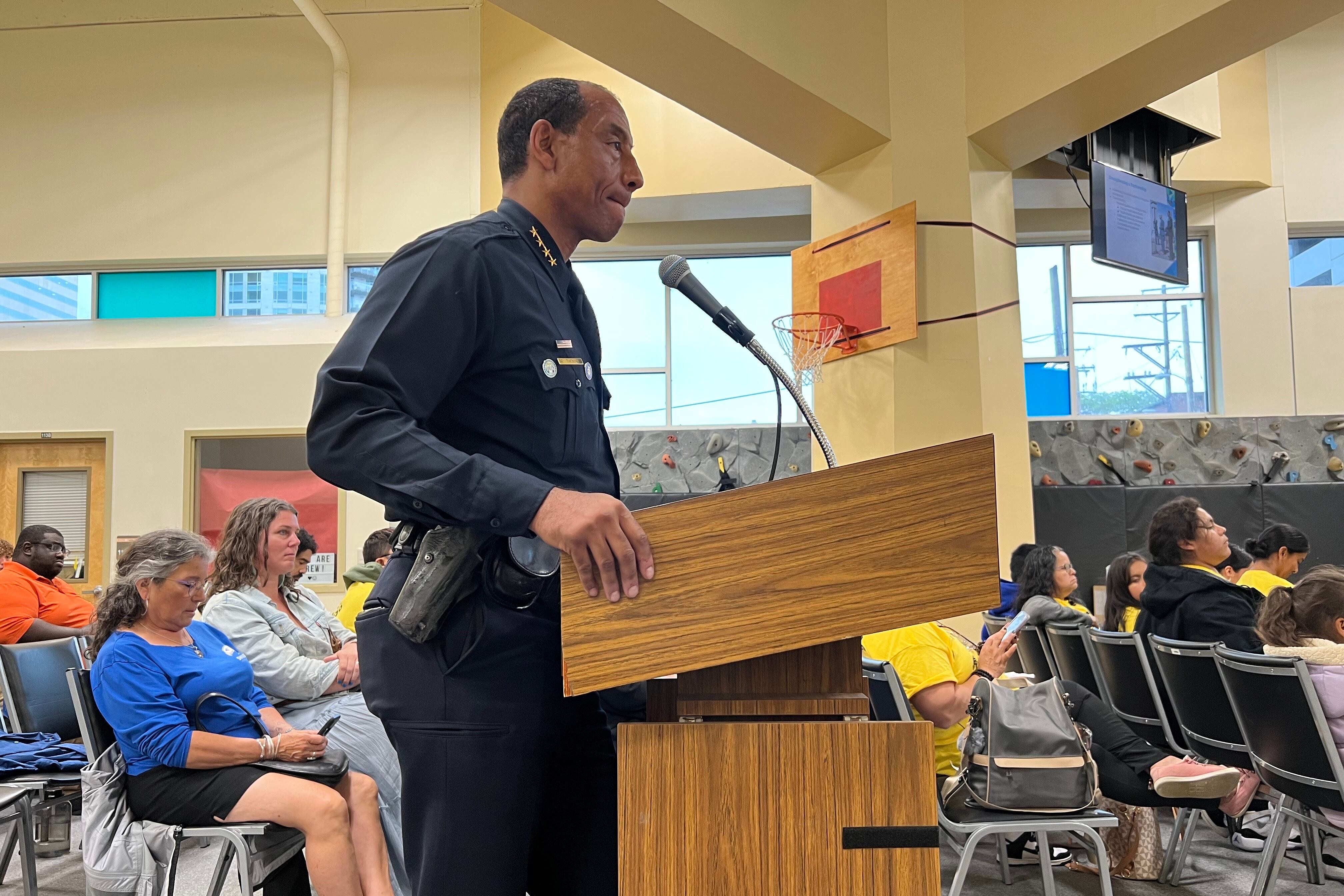 Denver Police Chief Ron Thomas stands at a podium in the auditorium where the Denver school board holds public comment. You can see audience members seated behind him.