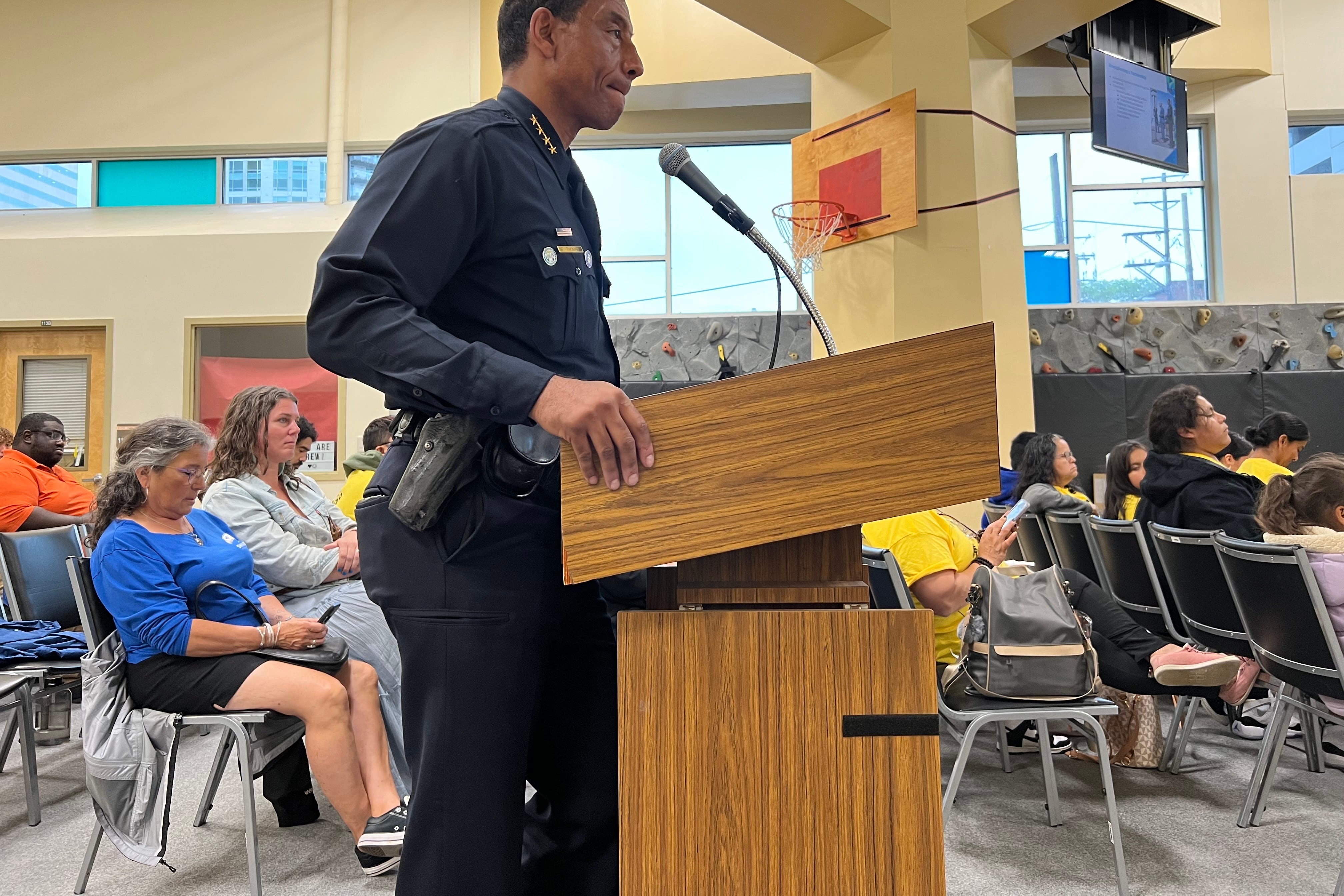 Denver Police Chief Ron Thomas stands at a podium in the auditorium where the Denver school board holds public comment. You can see audience members seated behind him.