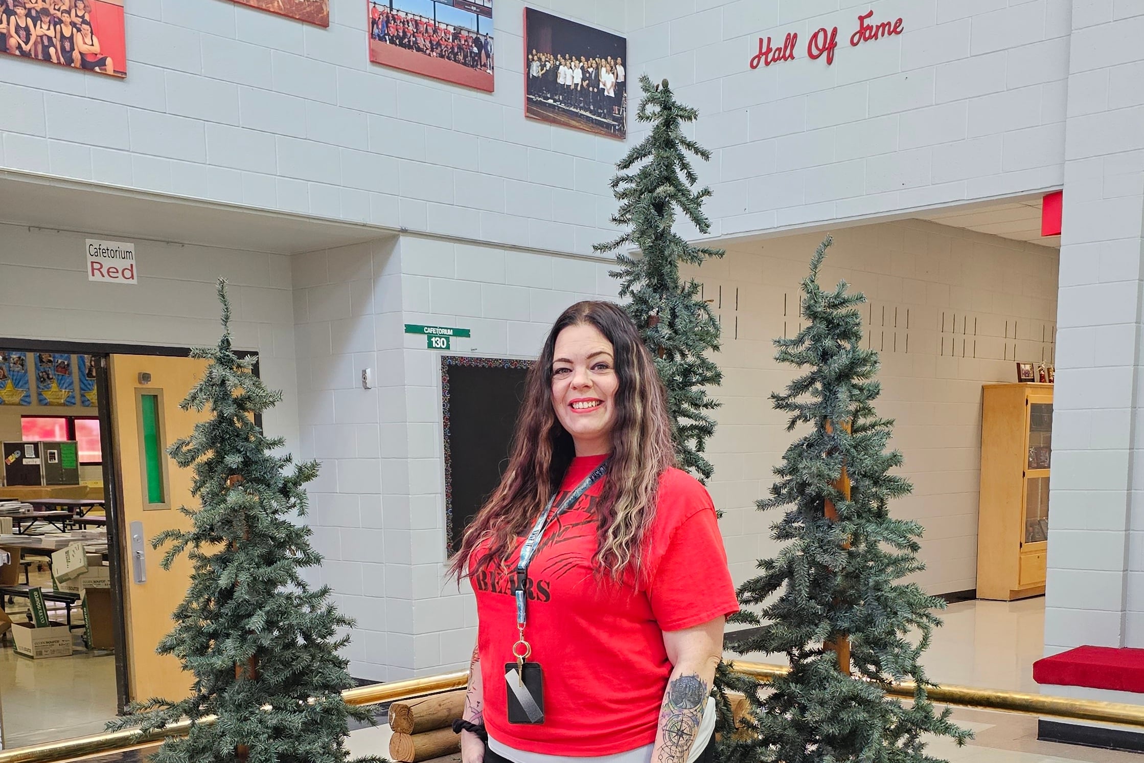 A woman in a red shirt stands next to three bear sculptures inside a school.