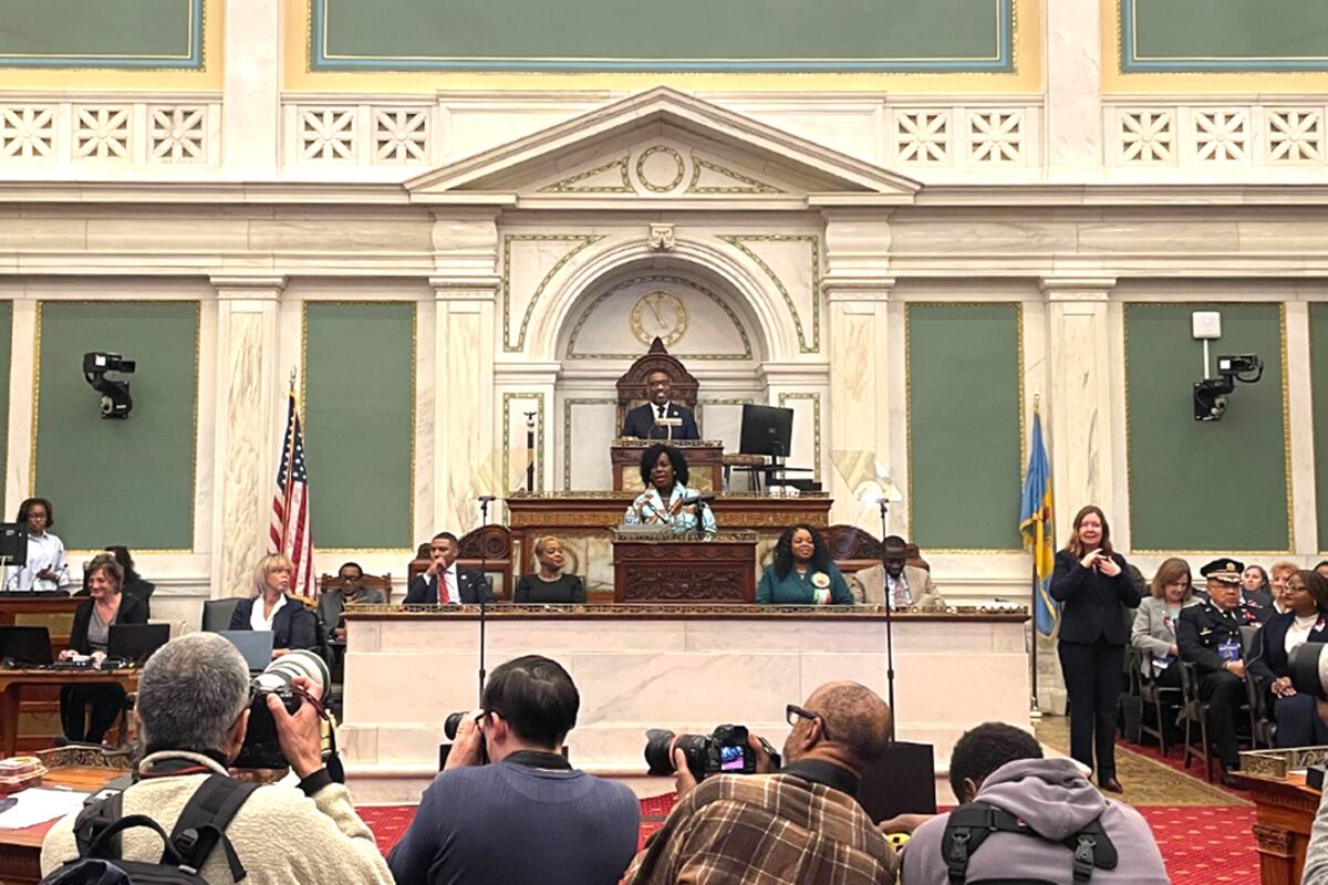 A woman stands at a podium in a grand room.