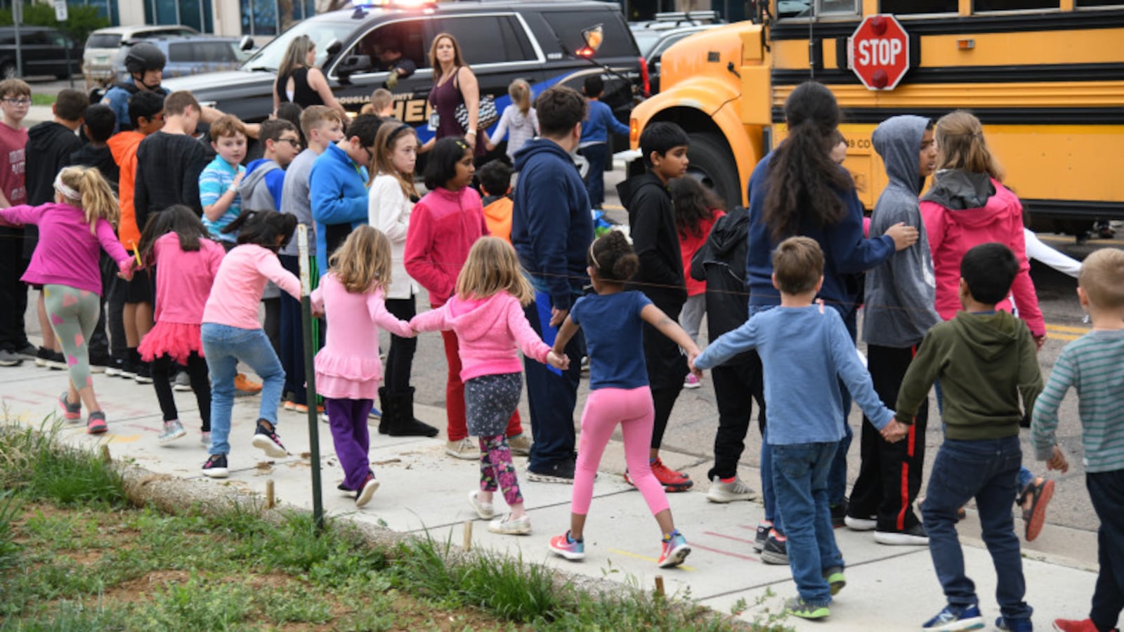 Students are escorted to a school bus in front of STEM School Highlands Ranch after a shooting.
