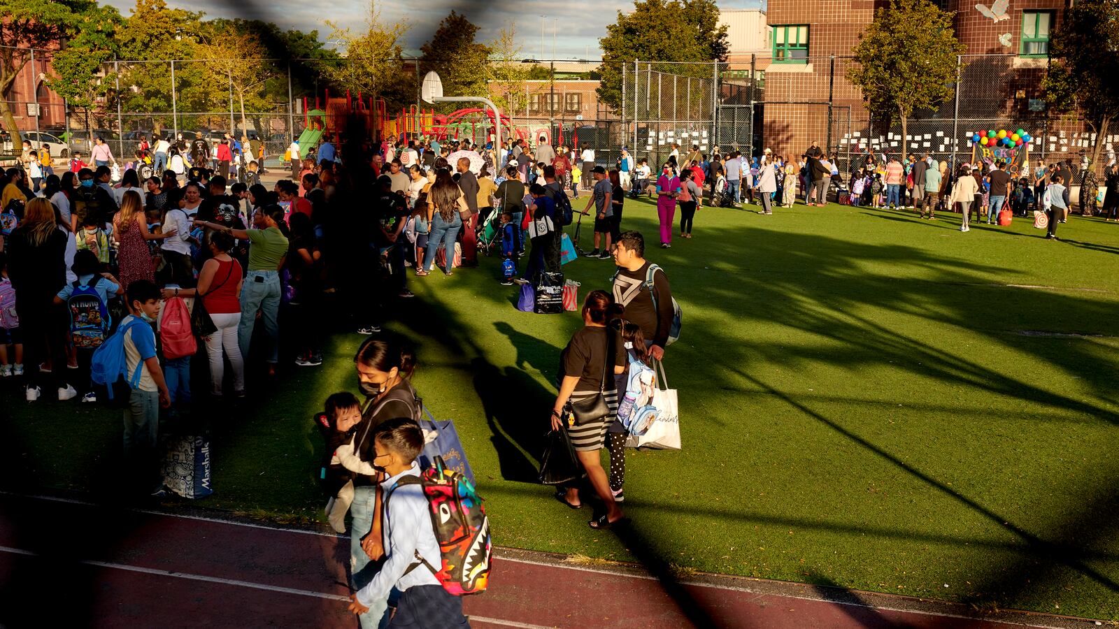 Students and parents are seen waiting on a field before sending their children to the first day of school.