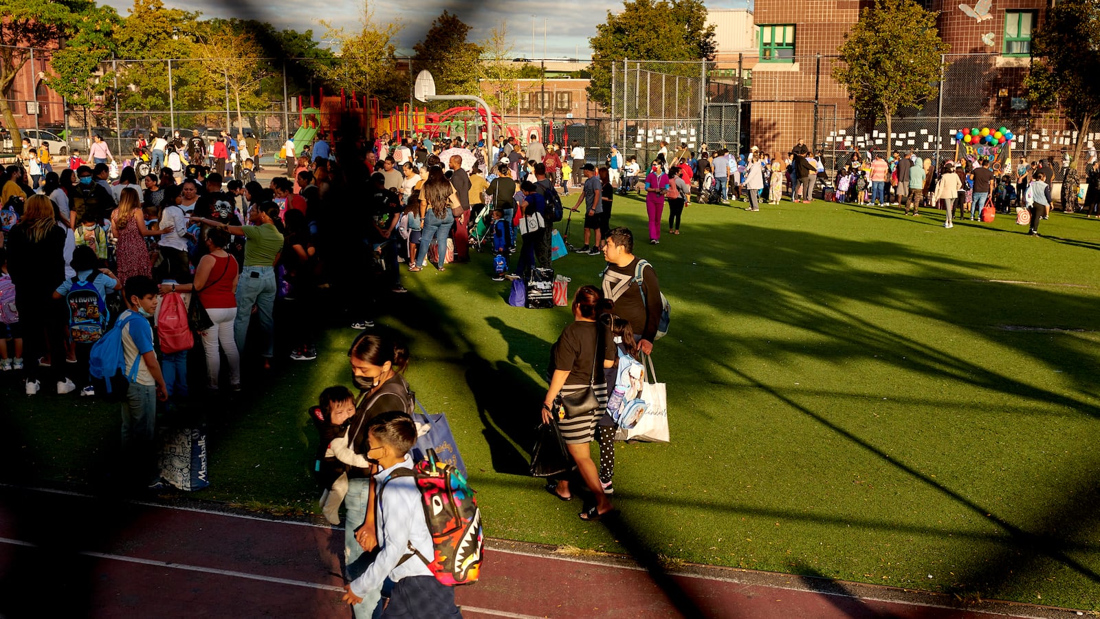 Students and parents are seen waiting on a field before sending their children to the first day of school.