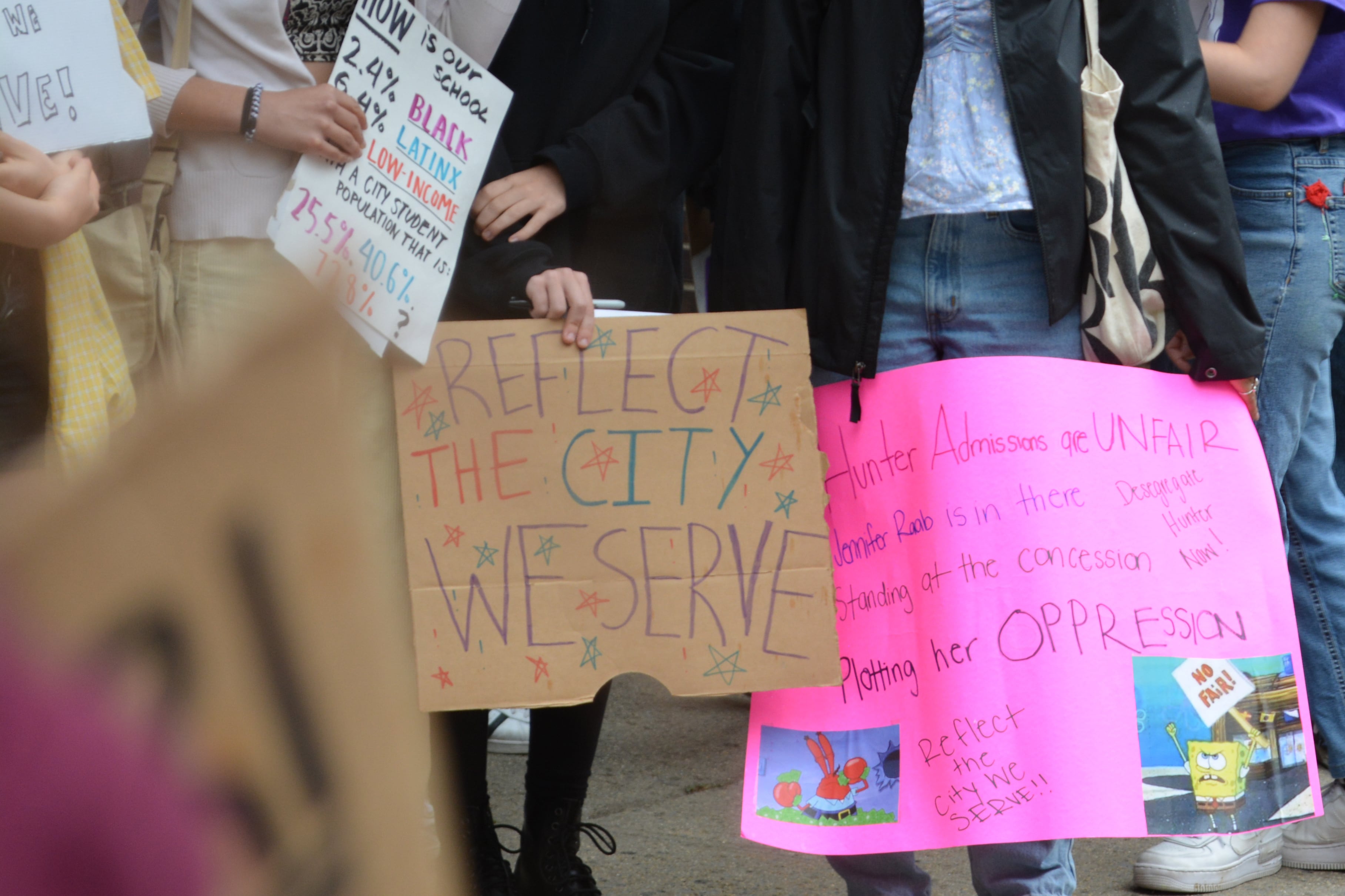 A photograph of a group of protestors holding colorful signs outside.