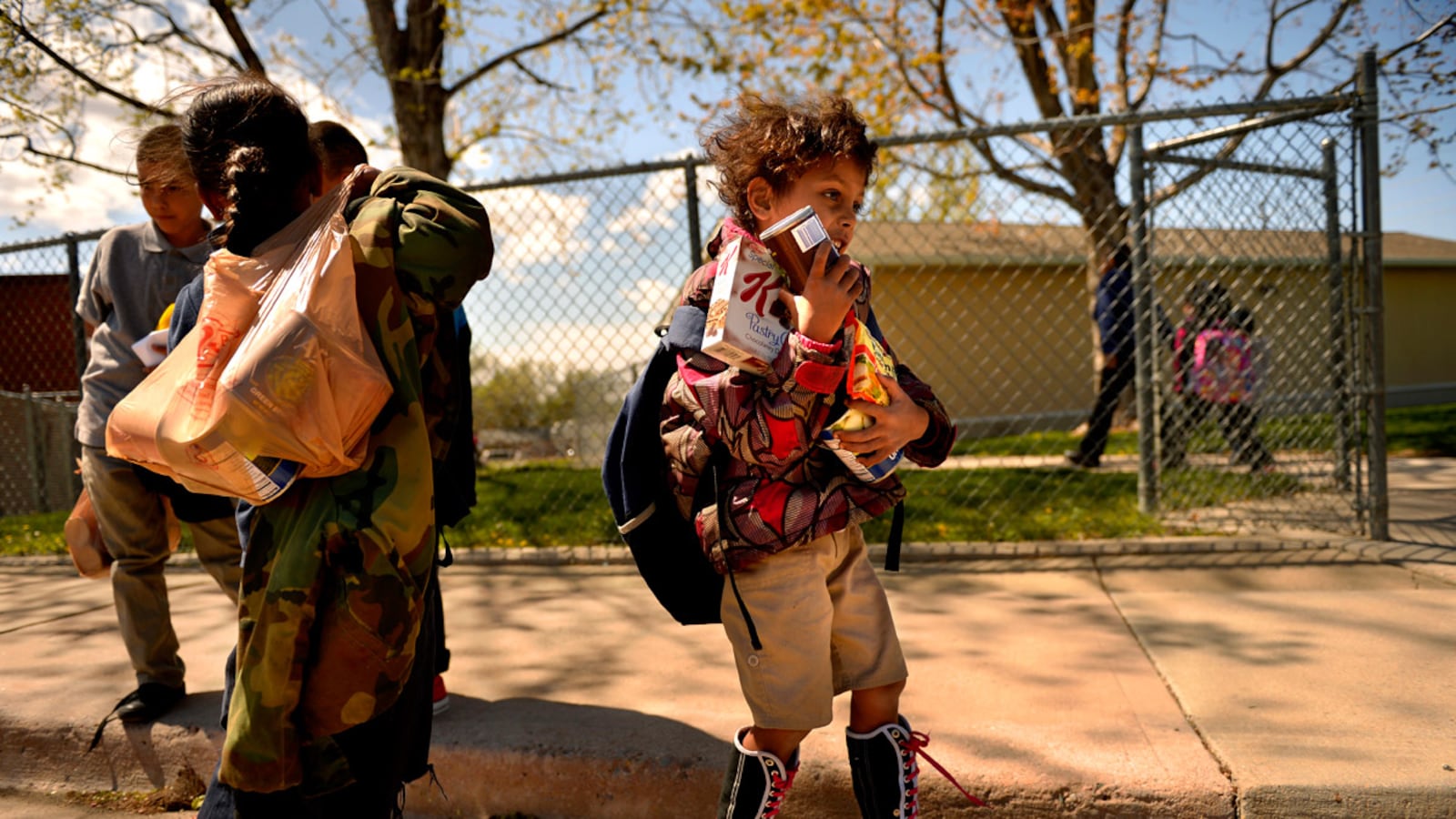 Homeless children in Aurora walk with bags of donated food after school.