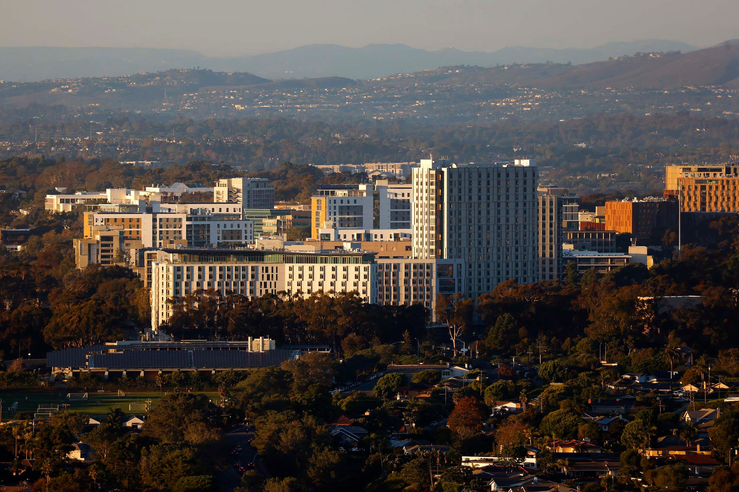 An aerial photograph of student housing high rise buildings surrounded by rolling hills and houses.