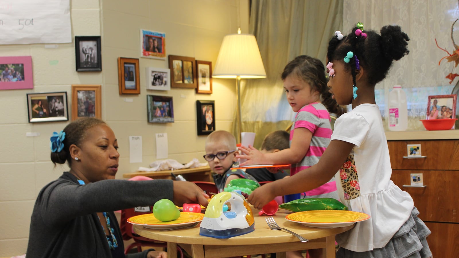 A teacher sits with preschoolers as they play in a preschool classroom at the Day Early Learning Lilly Center.