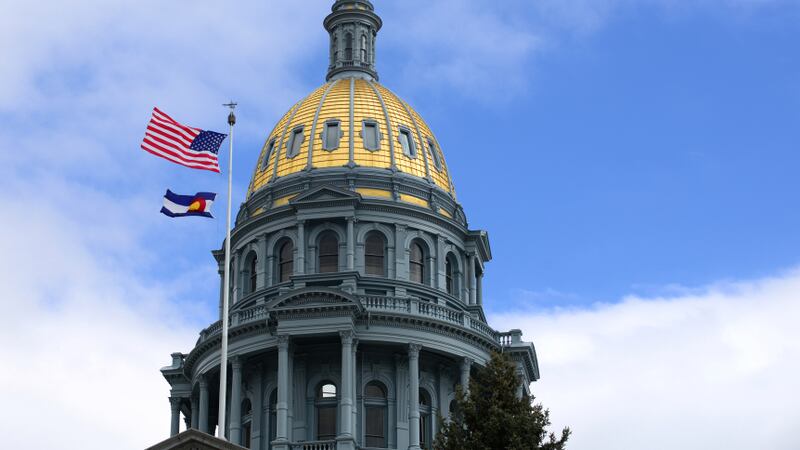 Colorado state Capitol building in Denver, Colorado, with the U.S. and state flags in front of a cloudy sky