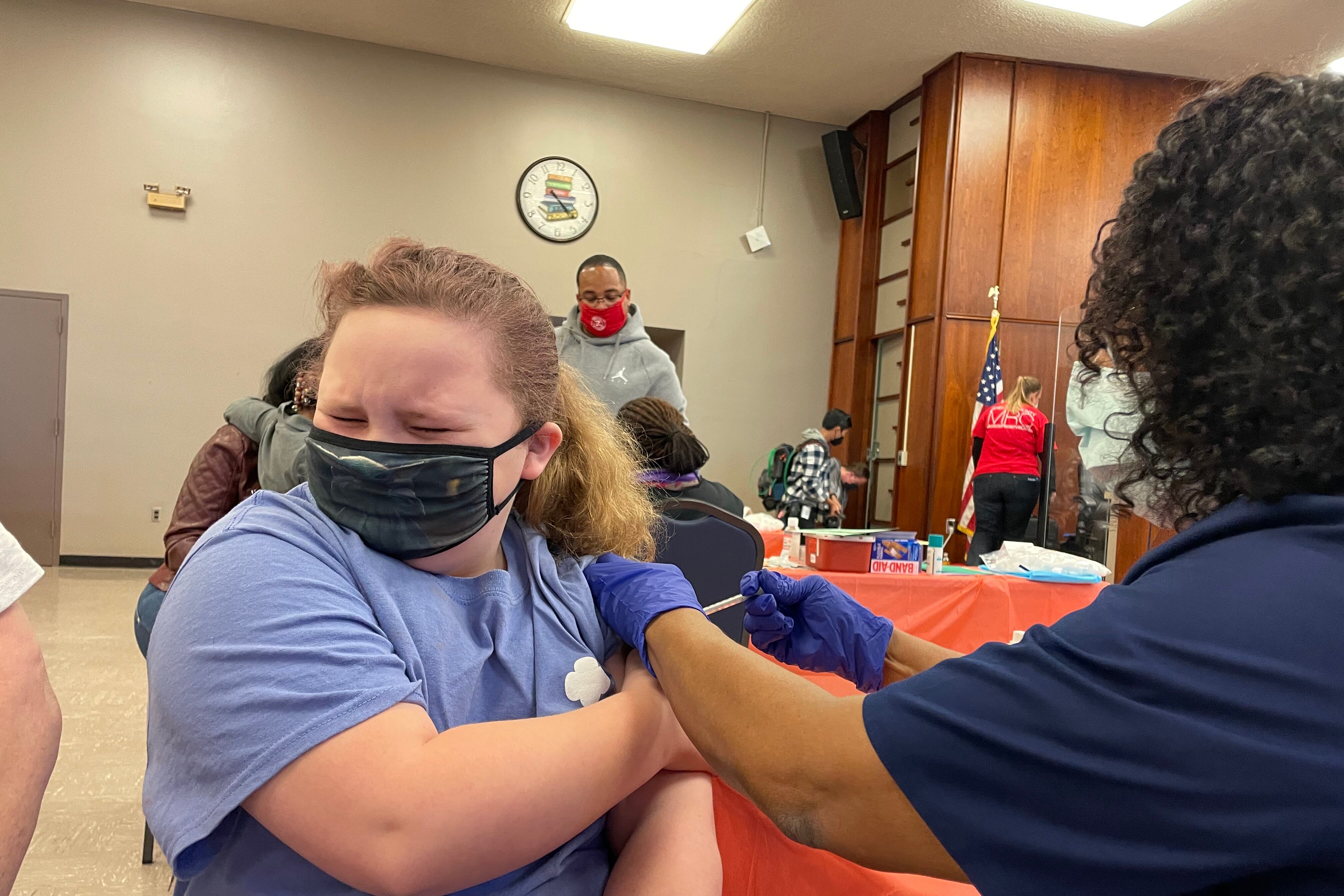 A girl winces as a nurse gives her the COVID shot.