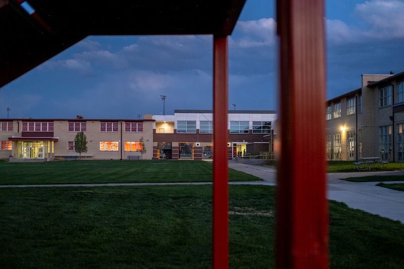 Buildings on a campus with a green grassy lawn in the middle.