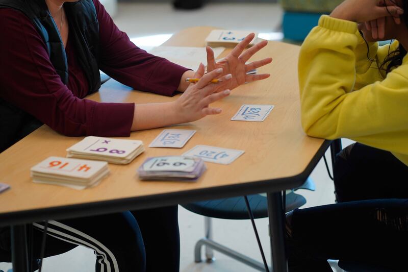 Two people sit at a table working on math flashcards.