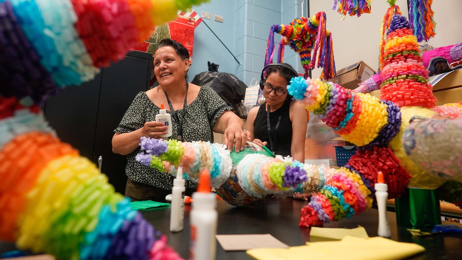 Two women make a colorful star-shaped piñata.