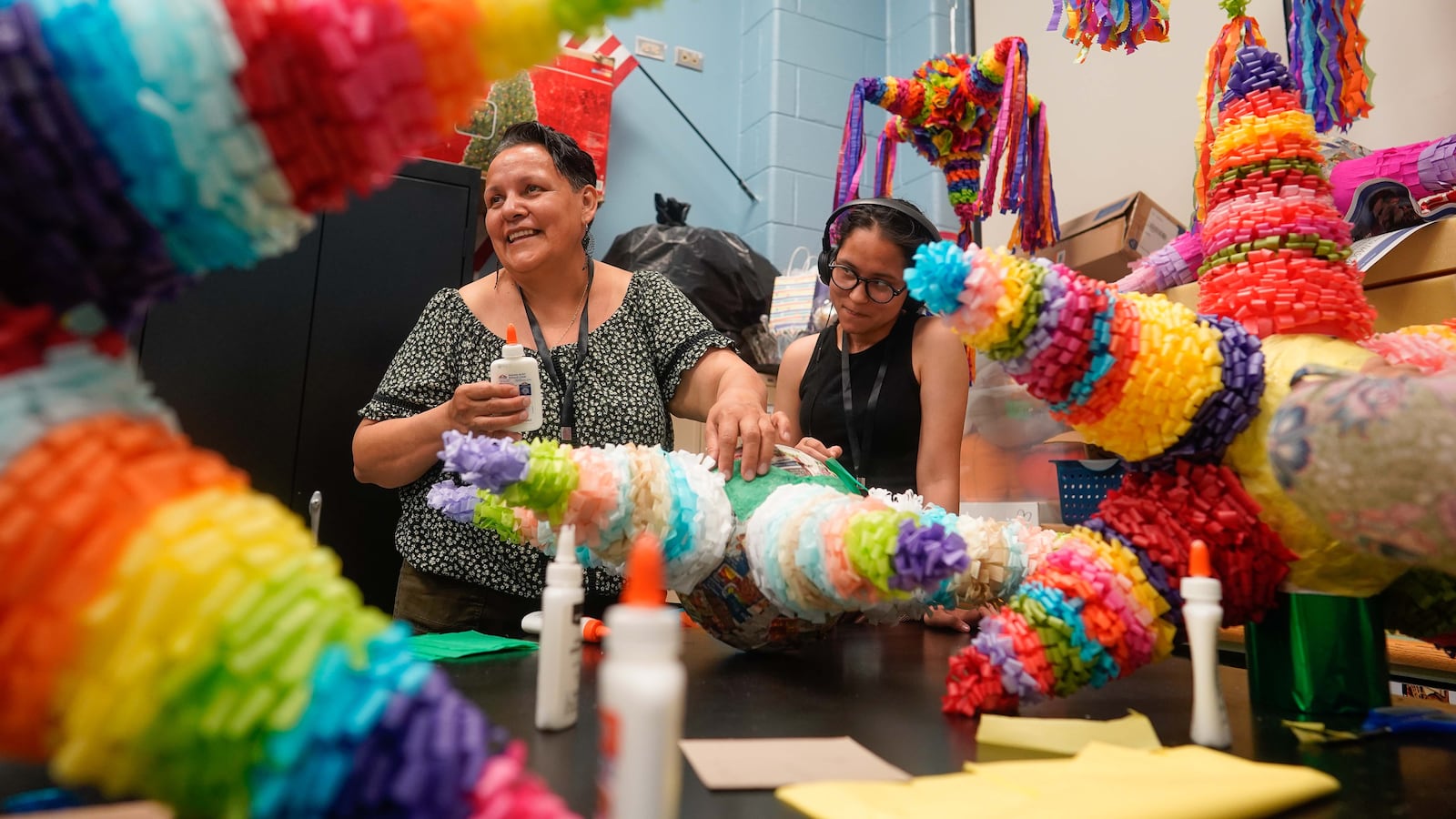 Two women make a colorful star-shaped piñata.