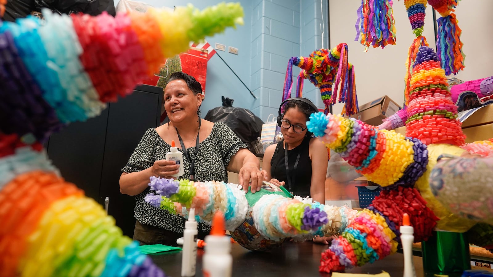 Two women make a colorful star-shaped piñata.
