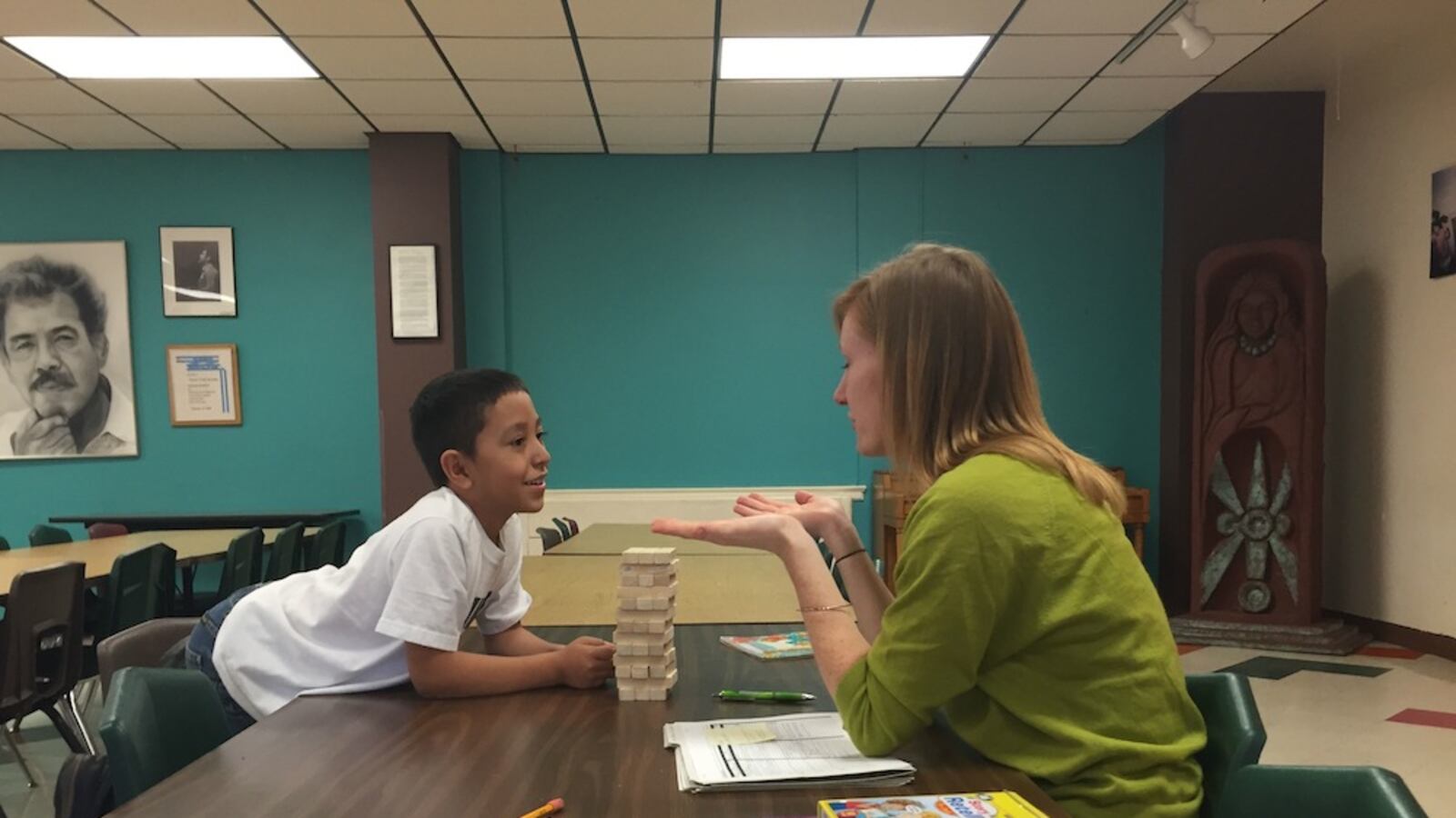 A student and teacher at Escuela Tlatelolco work together. "Did the mom FELL something or DROP something?" "She dropped it."