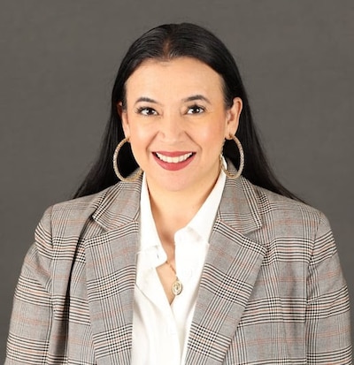 A portrait of a woman with dark hair, suit jacket and white blouse.