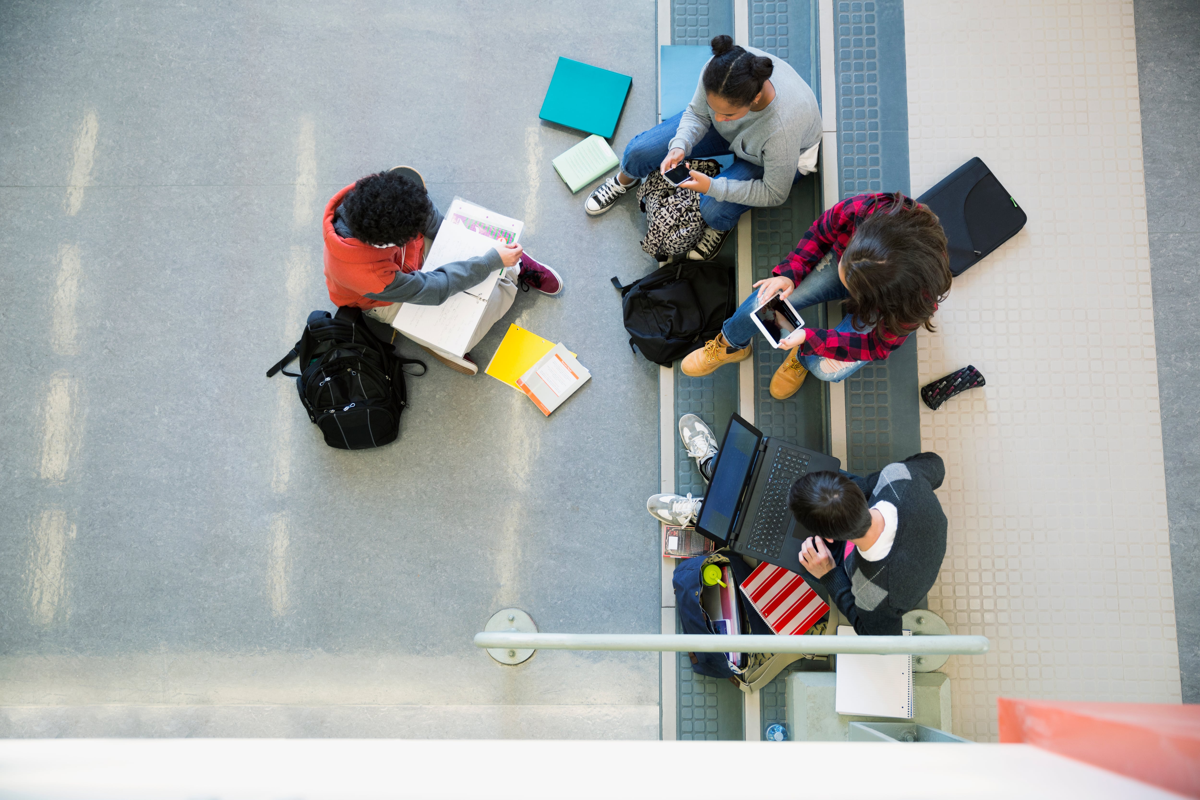 A bird's eye view of four students, backpacks and books.