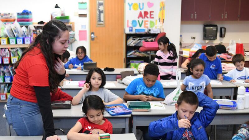 Teacher Hannah Maldonado wears a red T-shirt while looking at first graders doing work at rows of desks at Denver’s Barnum Elementary School in February 2019.
