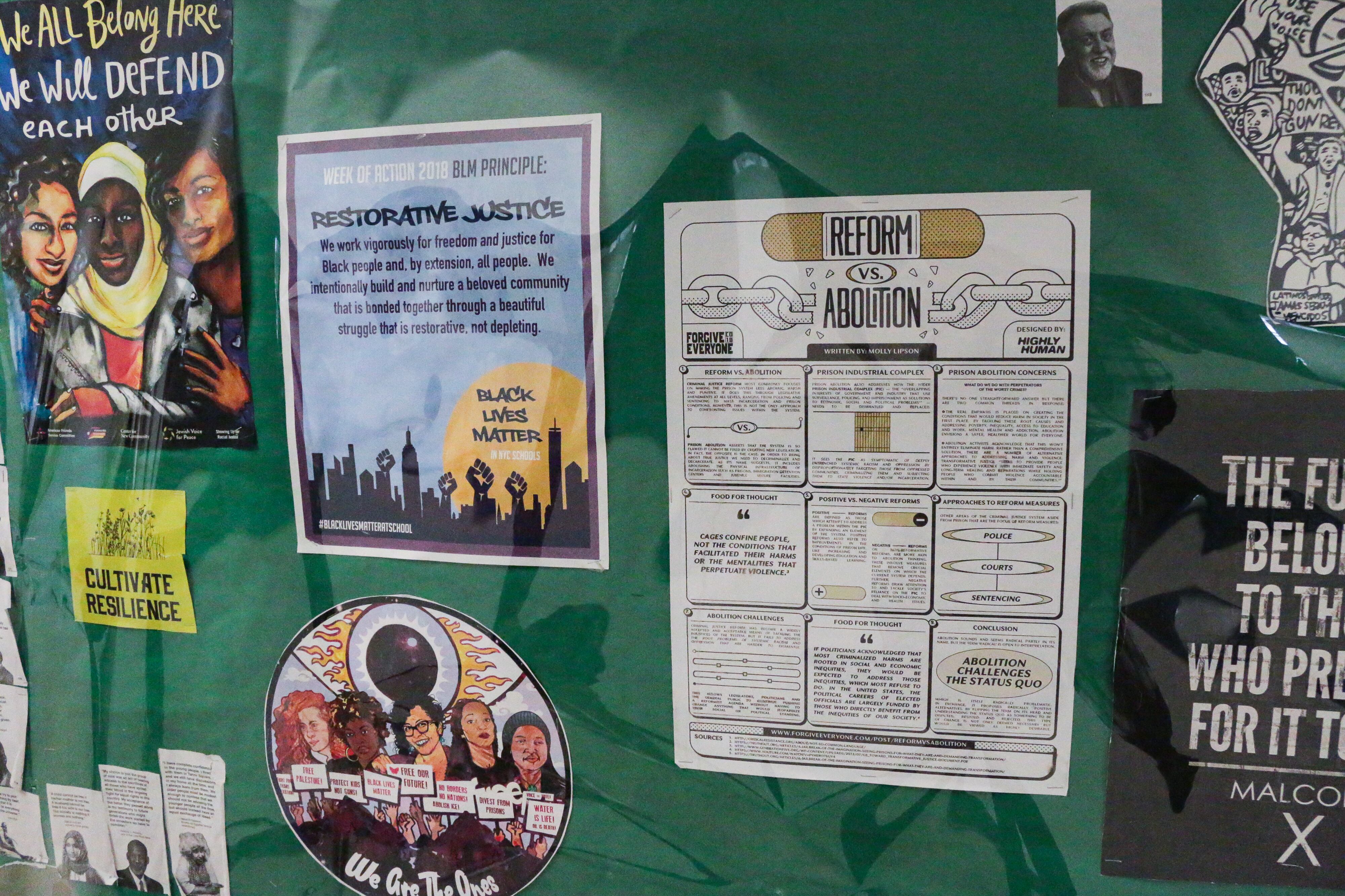 Posters attached to a green paper wall.