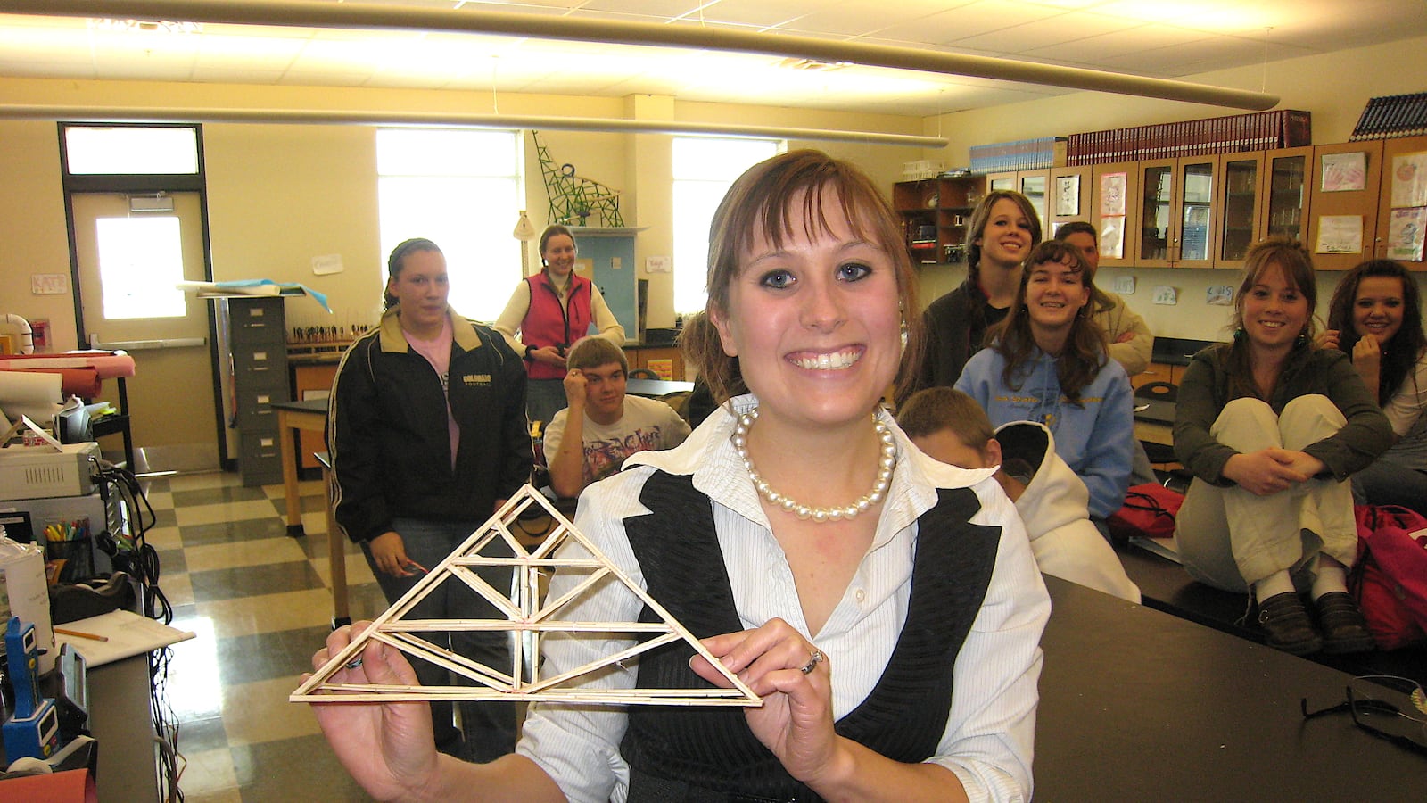 Shannon Wachowski, a science teacher at Platte Valley High School, holds a toothpick bridge as a her students look on.