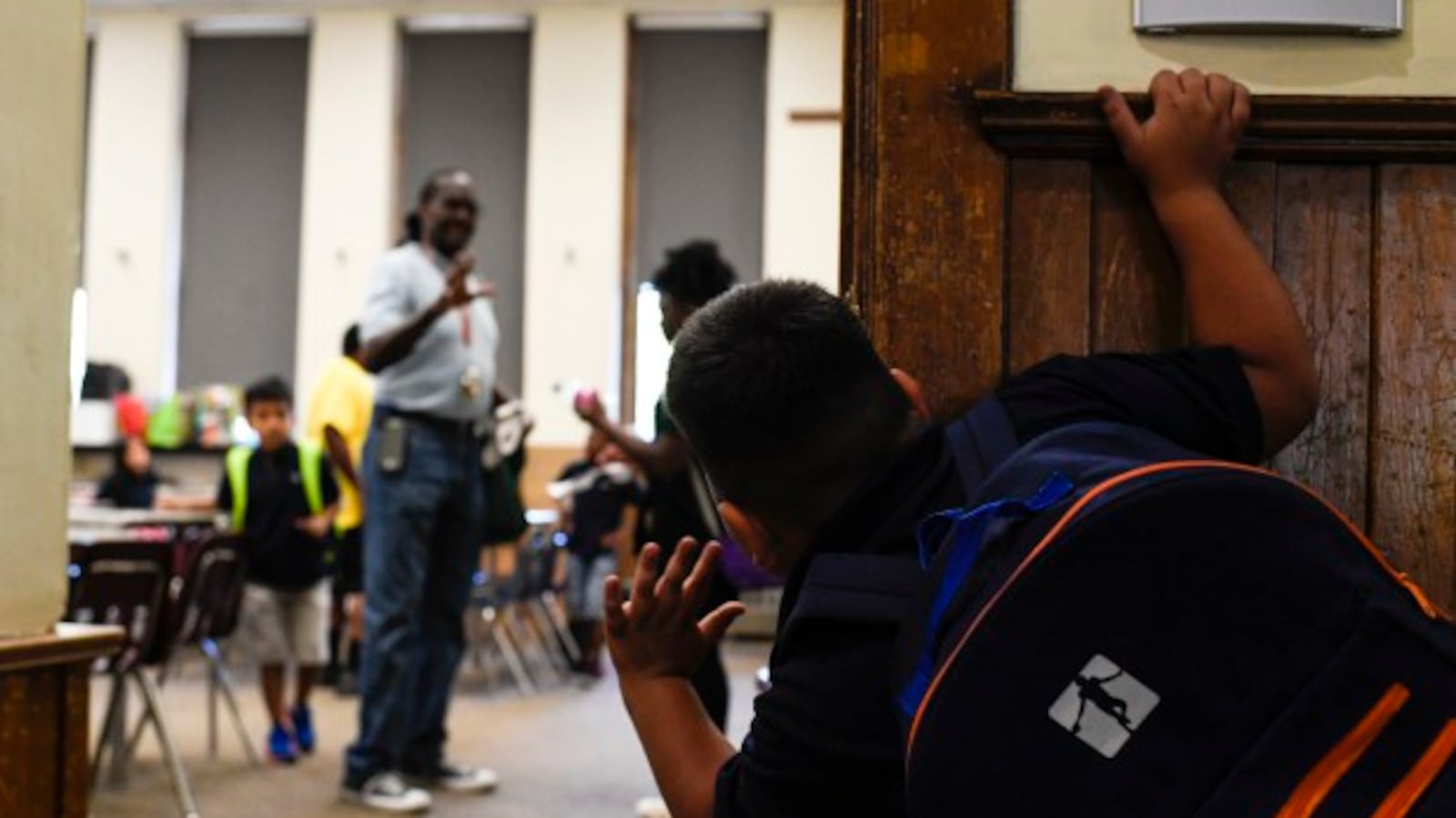 Sebastian Cruz waves to Rev. Leon Kelly as he works with children in a classroom during his after-school program at Wyatt Academy in September 2018.
