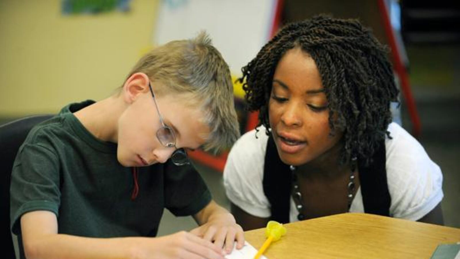 A teacher helps a student who has cerebral palsy.