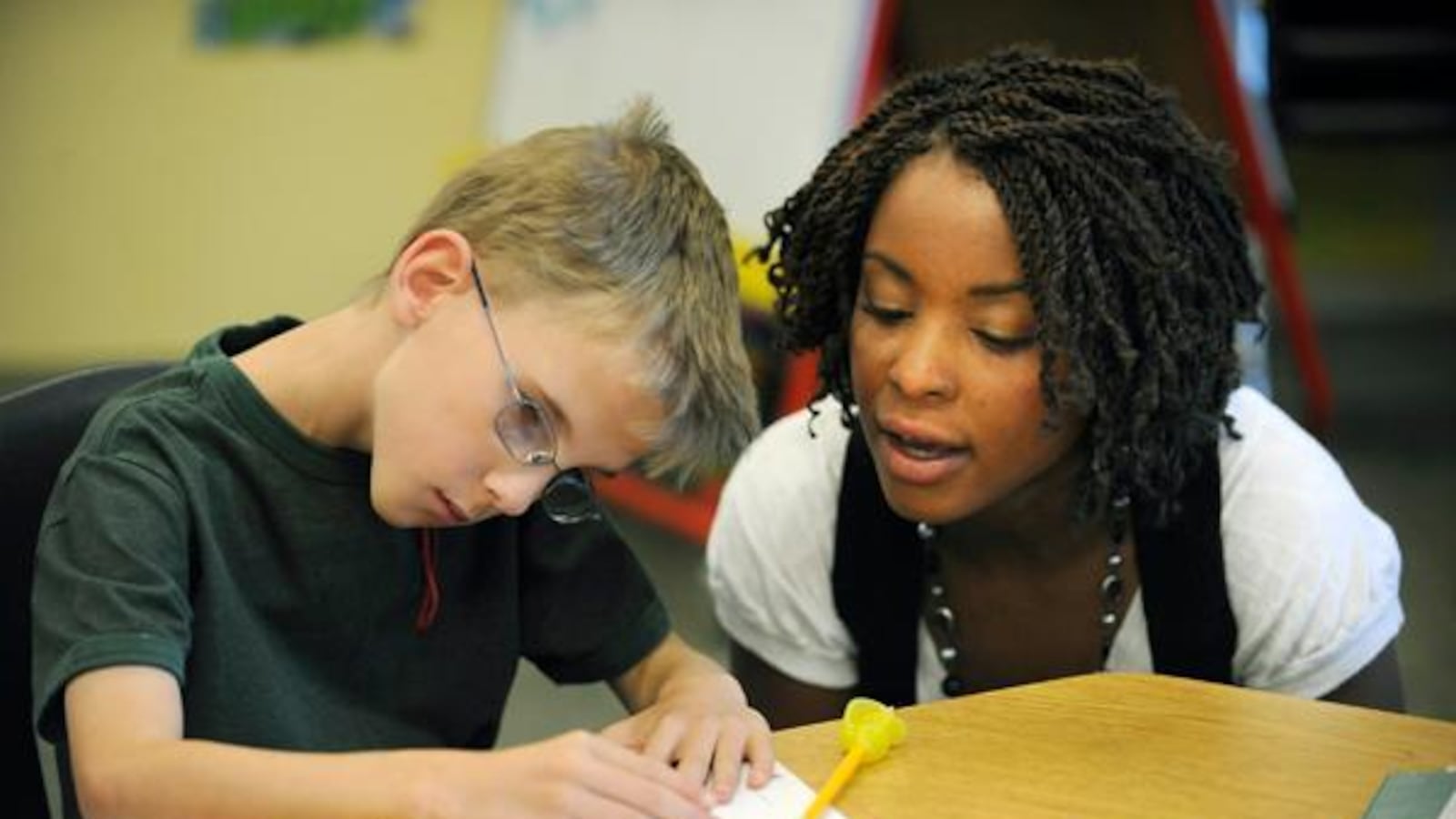 A teacher helps a student who has cerebral palsy.