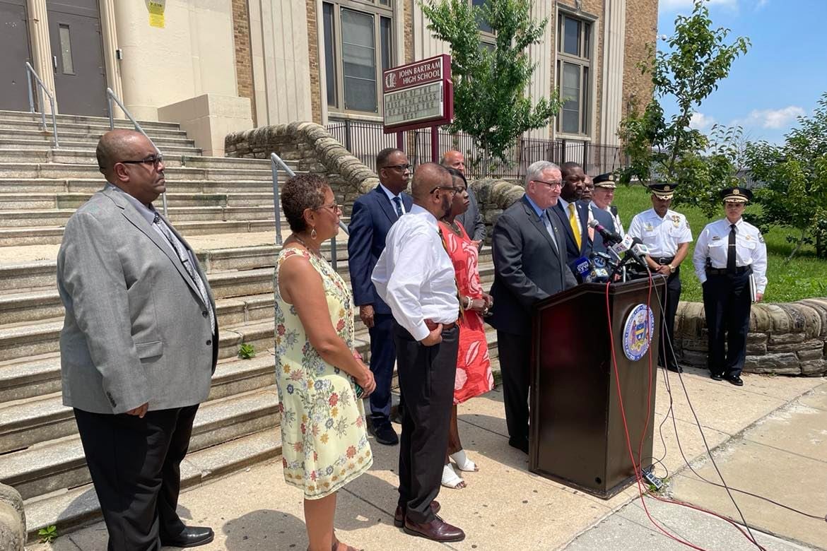 Philadelphia school, city and police officials on the steps of John Bartram High School in Southwest Philadelphia Monday. One man stands at a podium. 