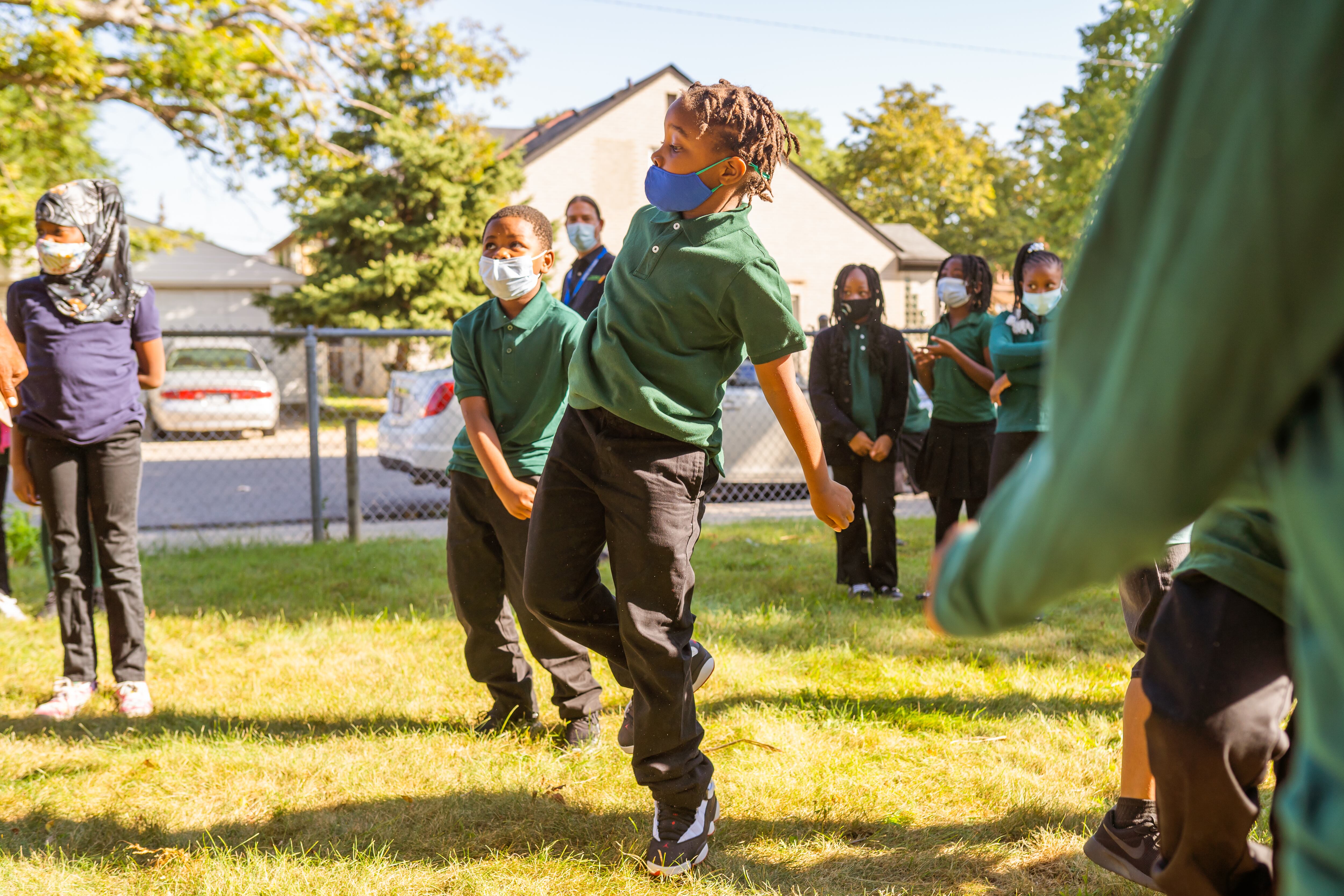 Students wearing green shirts dance together on the first day of school at Paul Robeson Malcom X Academy.