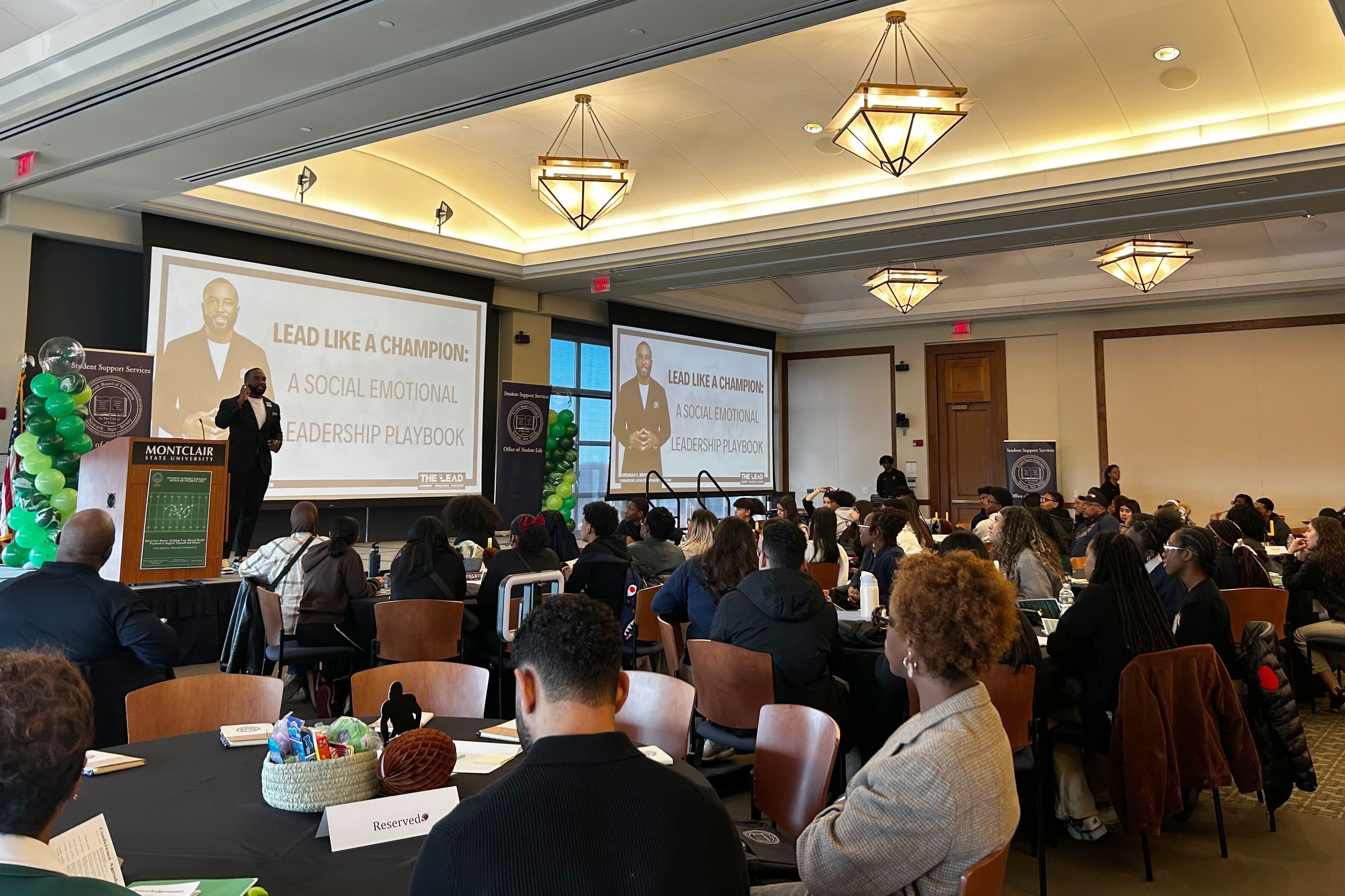 A large room of adults and students in a conference room.