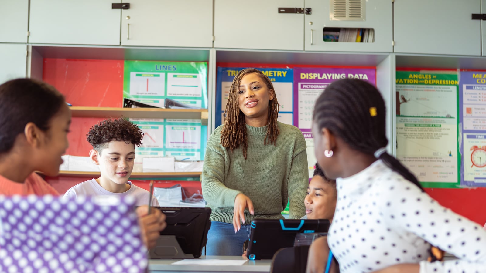 Young woman who is a teacher engages with students in a classroom.