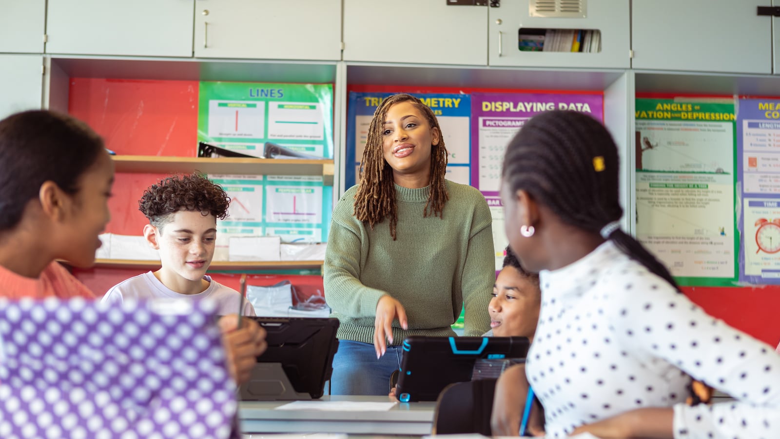 Young woman who is a teacher engages with students in a classroom.