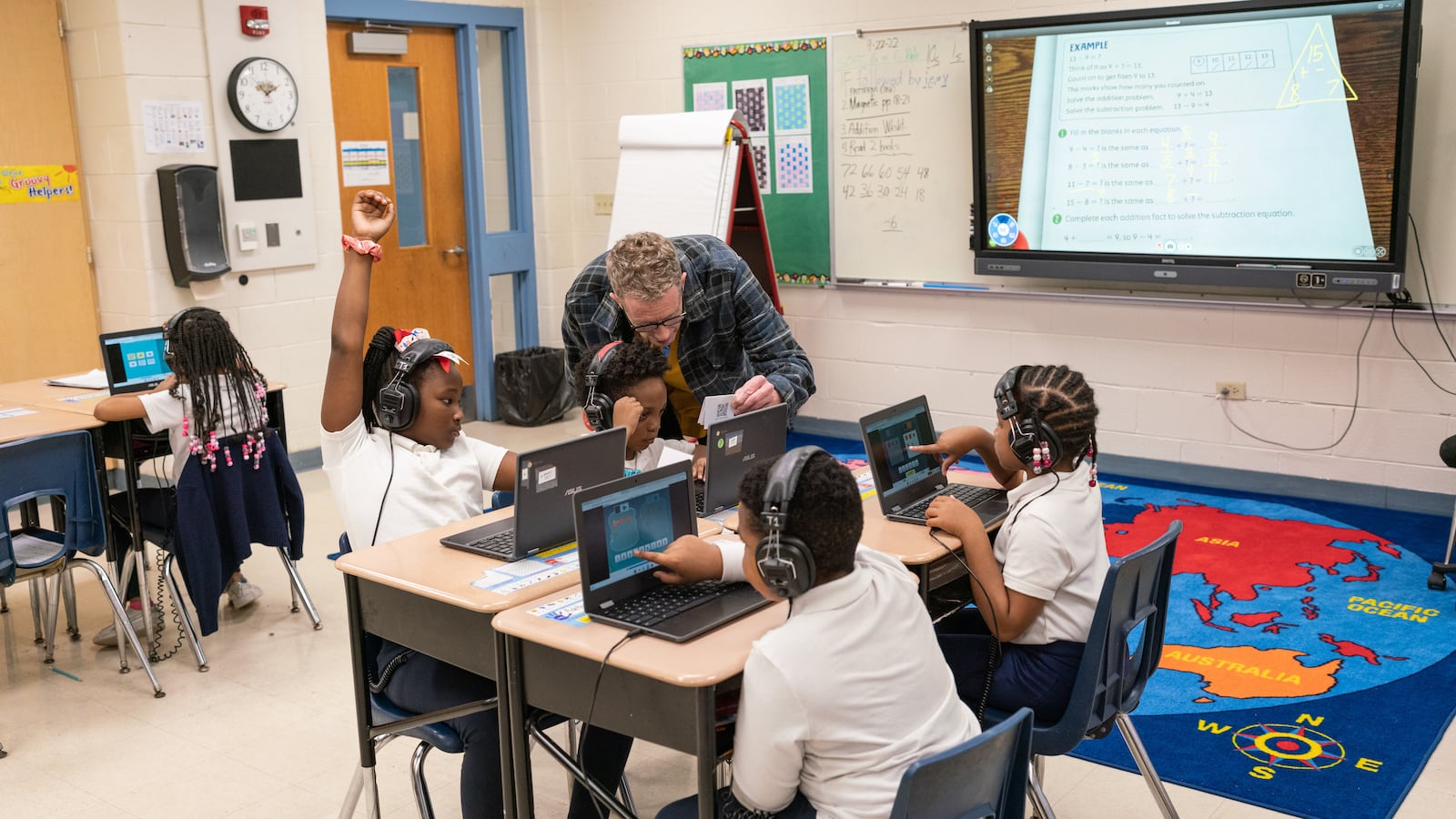 A teacher helps his students as they work on their computers in the classroom.