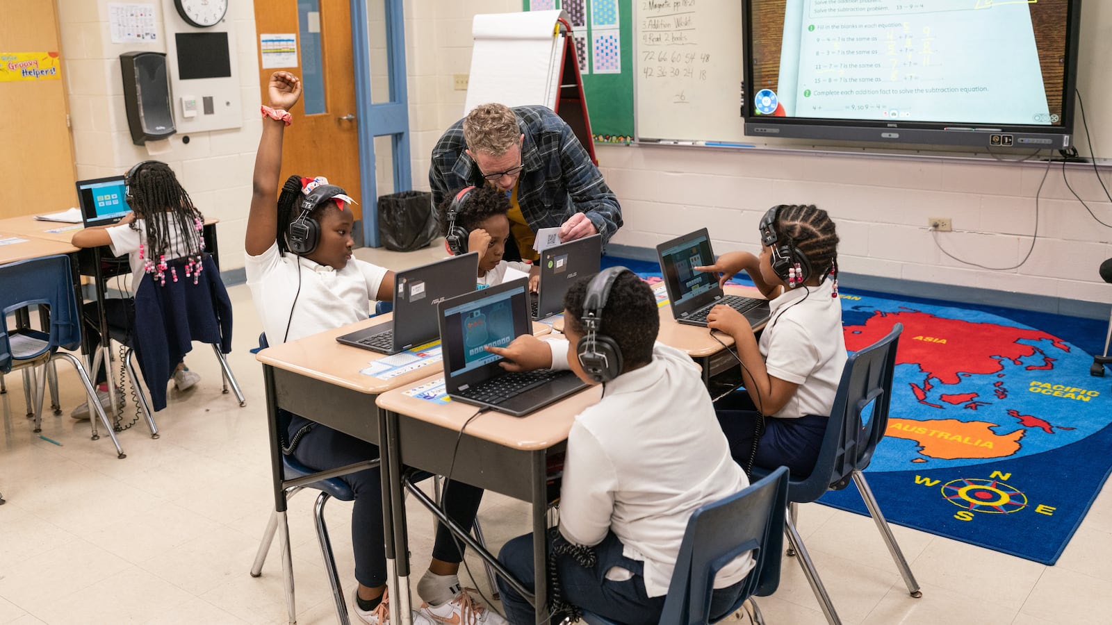 A teacher helps his students as they work on their computers in the classroom.