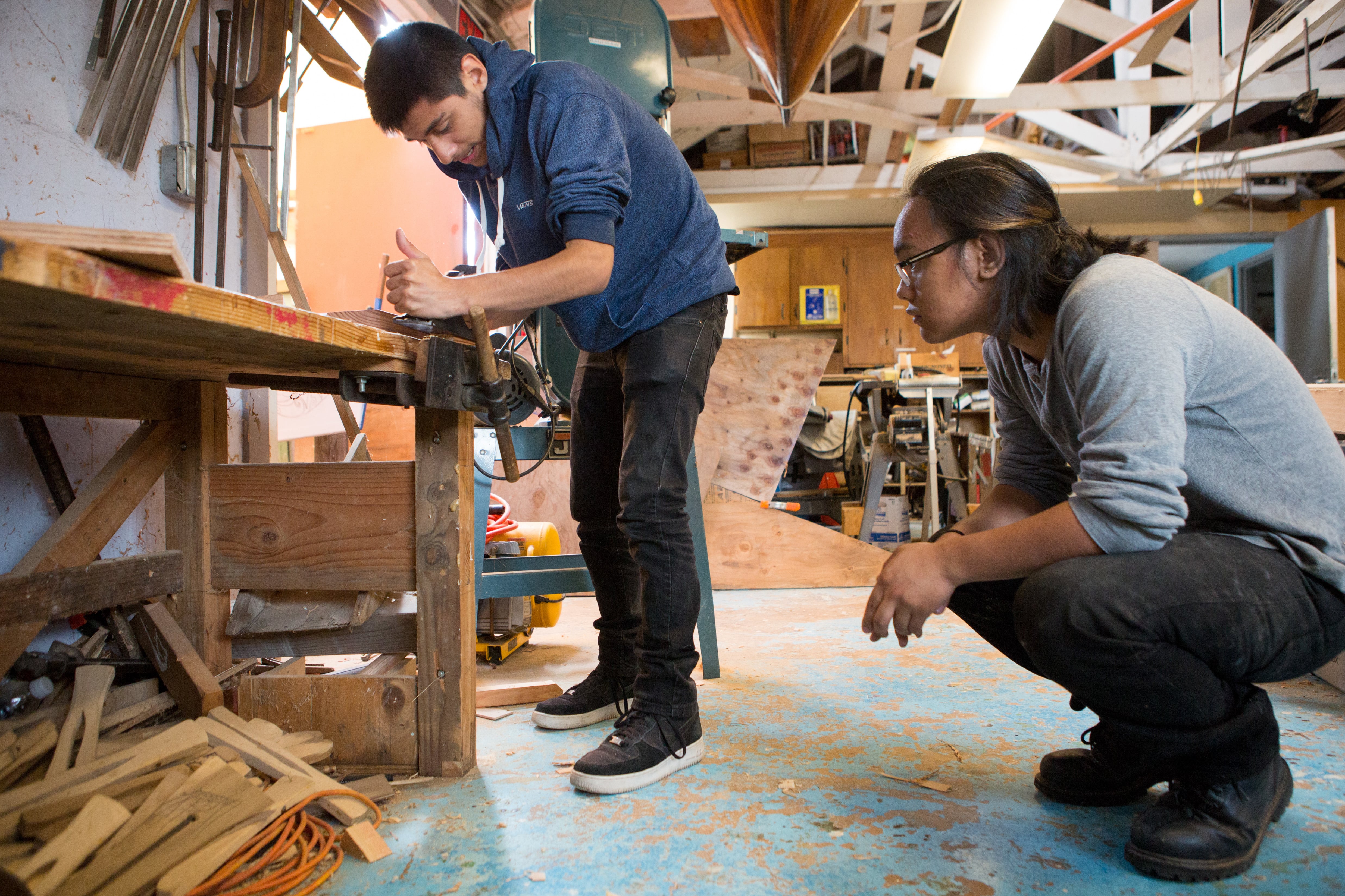 Two high school students work in a workshop.
