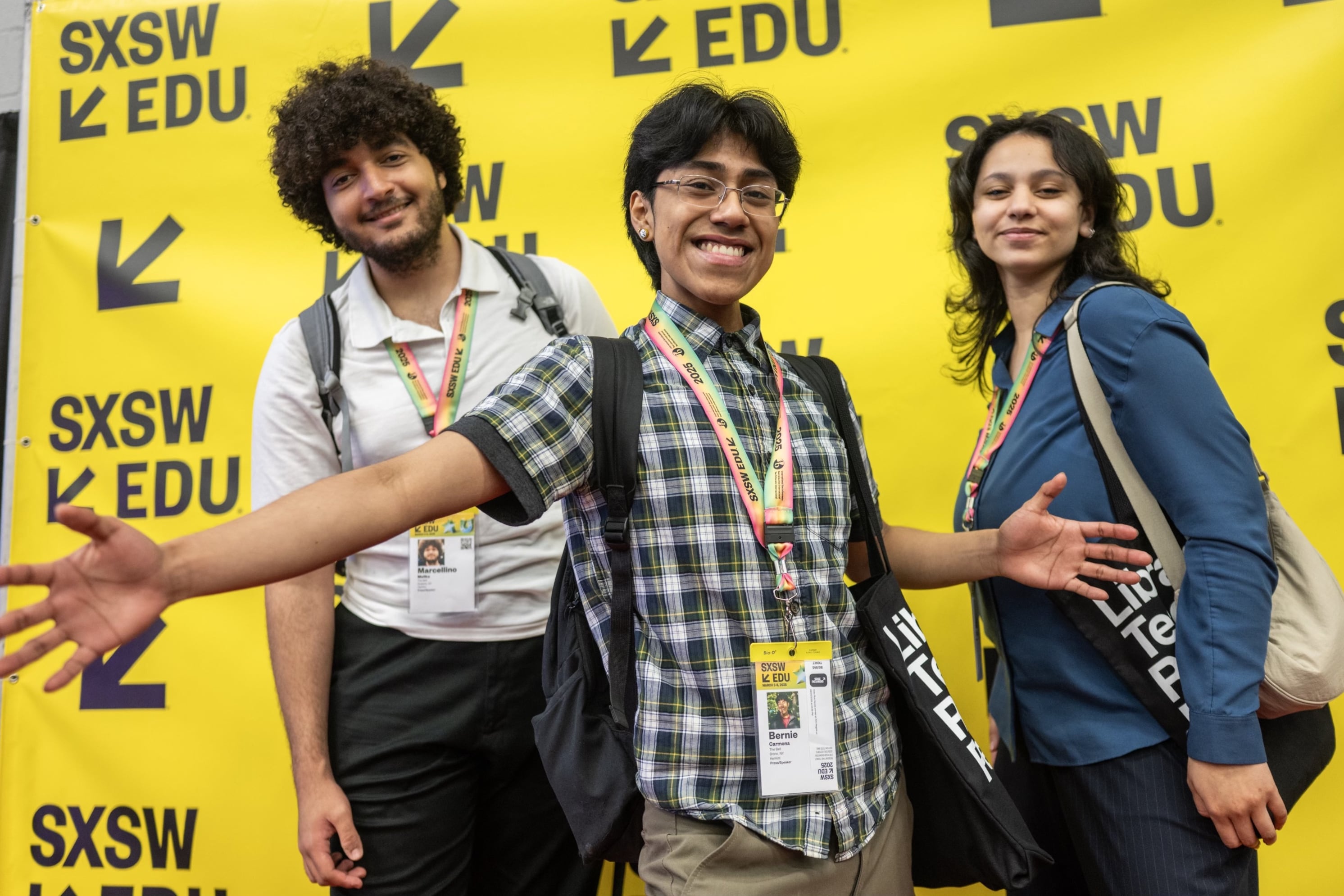 Three teens stand in front of a yellow background with black letters.