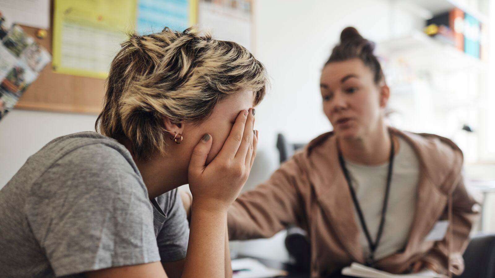 A school counselor comforts a teenage student.