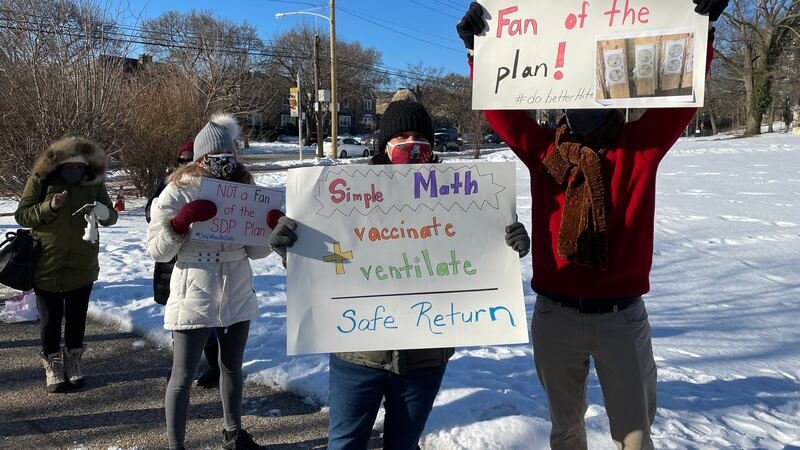 Teachers holding posters that read: "Not a fan of the plan!" and "Simple math: vaccinate + ventilate = safe return."