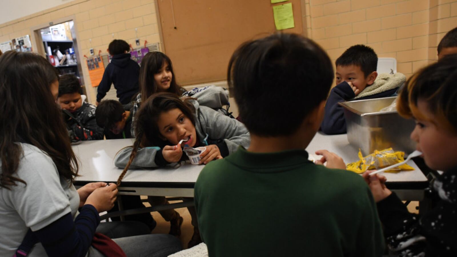 Idaly Clark, 10, eats a snack as her friend Flor Aguire,10, braids her hair during the after-school program at Munroe Elementary in southwest Denver.