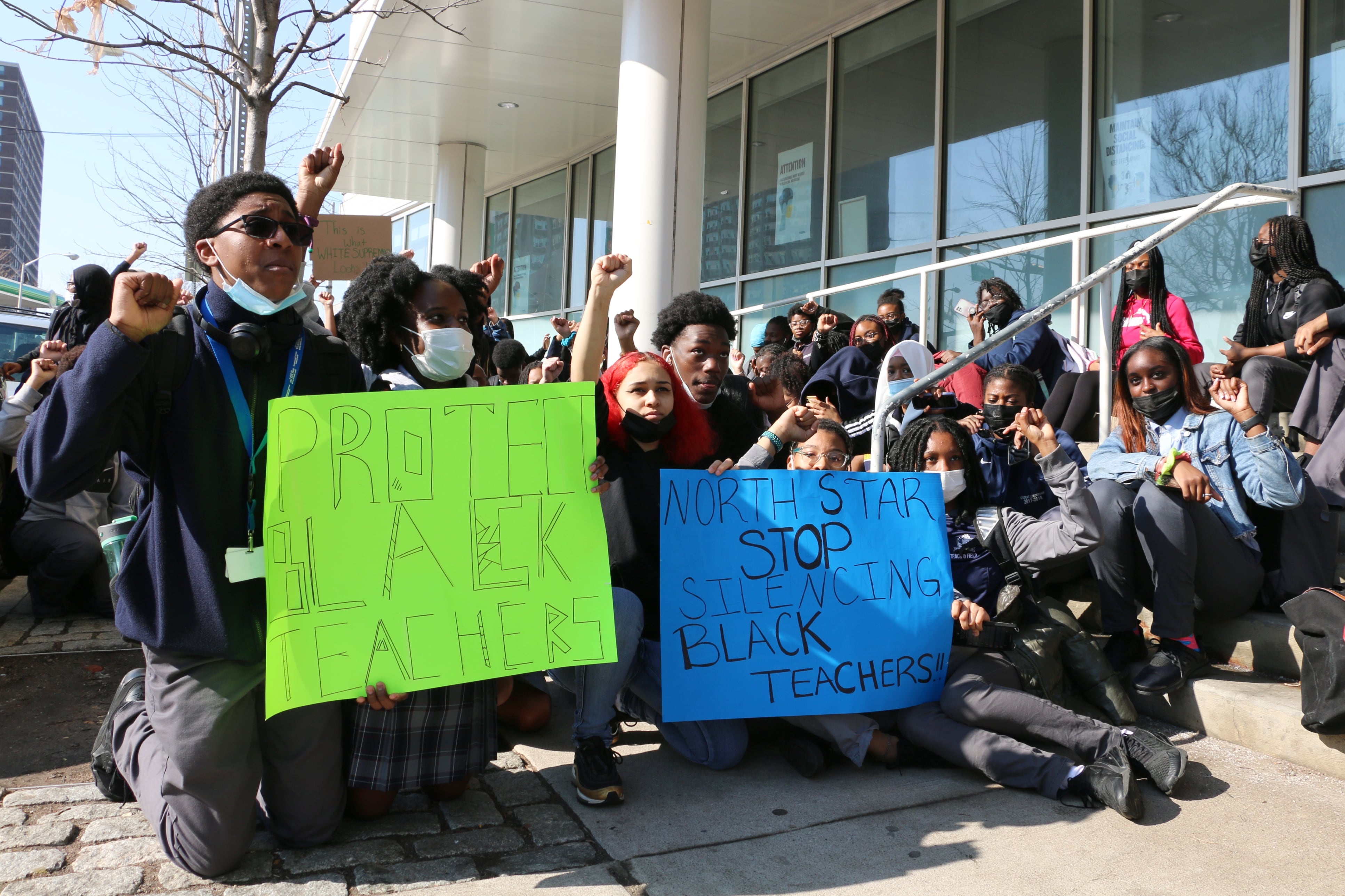 Students kneel, raise their fists, and hold up signs in a protest outside of North Star Academy in Newark.