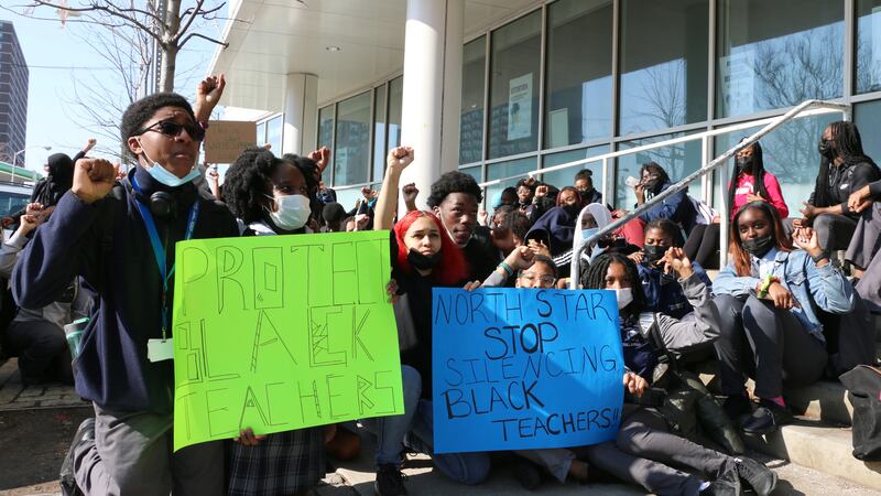 Students kneel, raise their fists, and hold up signs in a protest outside of North Star Academy in Newark.