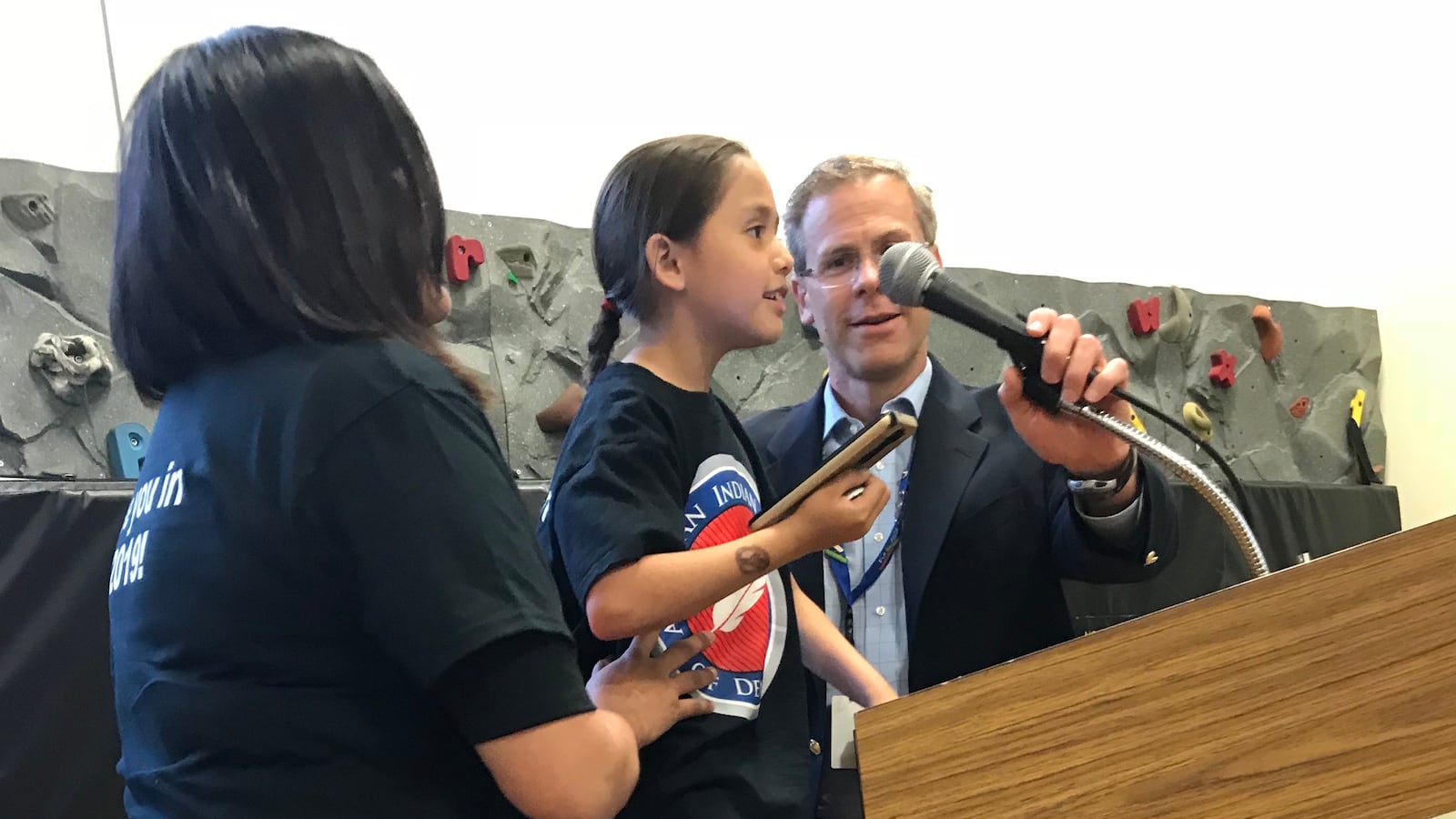 Tanski Chrisjohn gets help adjusting the microphone at a school board meeting from Denver Superintendent Tom Boasberg.