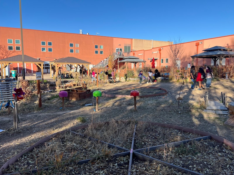 A photograph of a playground outside of a school building with a cloudless sky in the background.