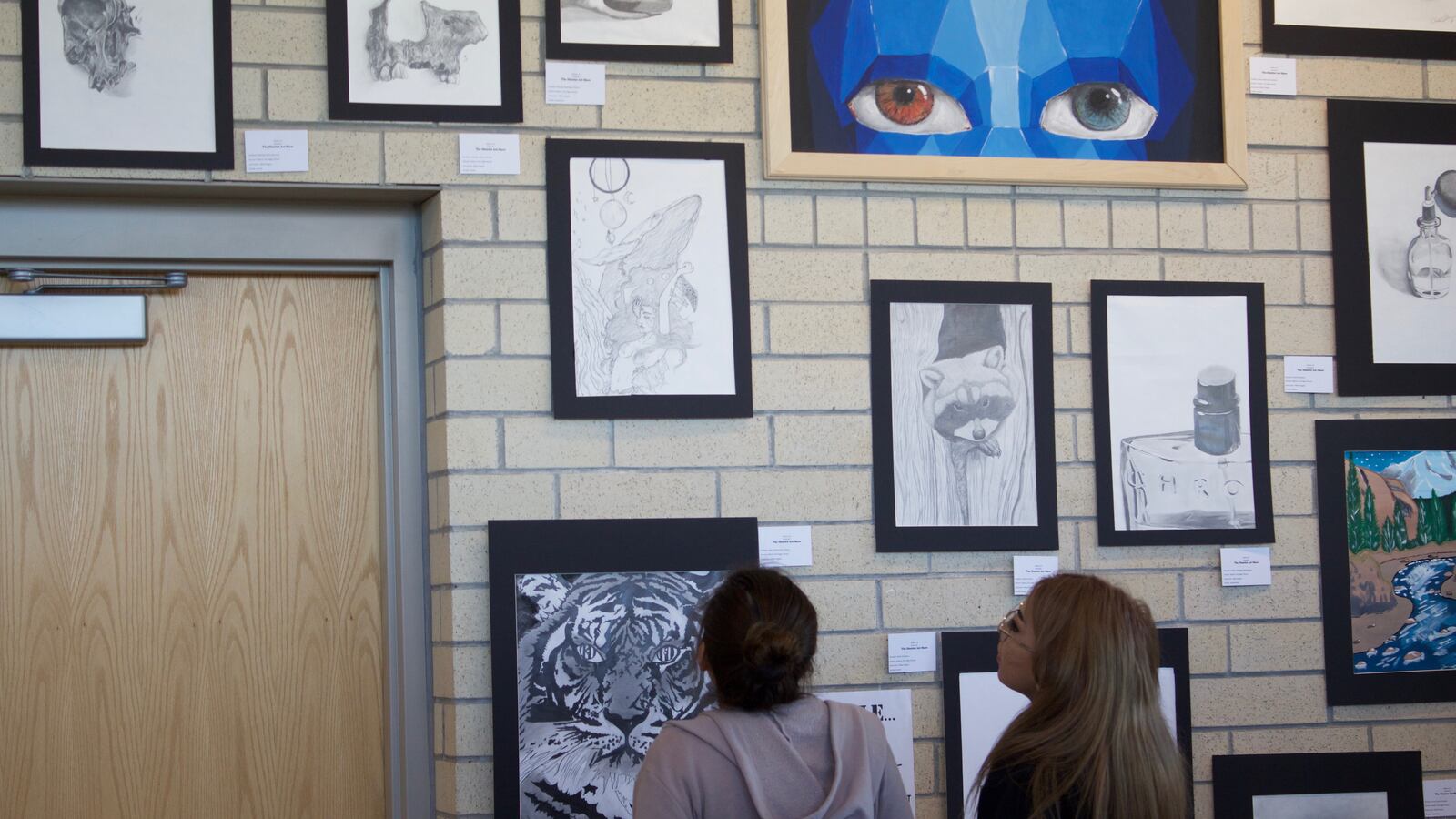 Art students at Adams City High School admire student artwork earlier this year ahead of the annual art show. (Photo by Yesenia Robles, Chalkbeat)