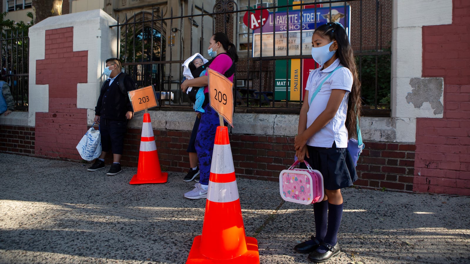 A girl waits at a large orange traffic cone on the first day of school at Newark’s Lafayette Street School.