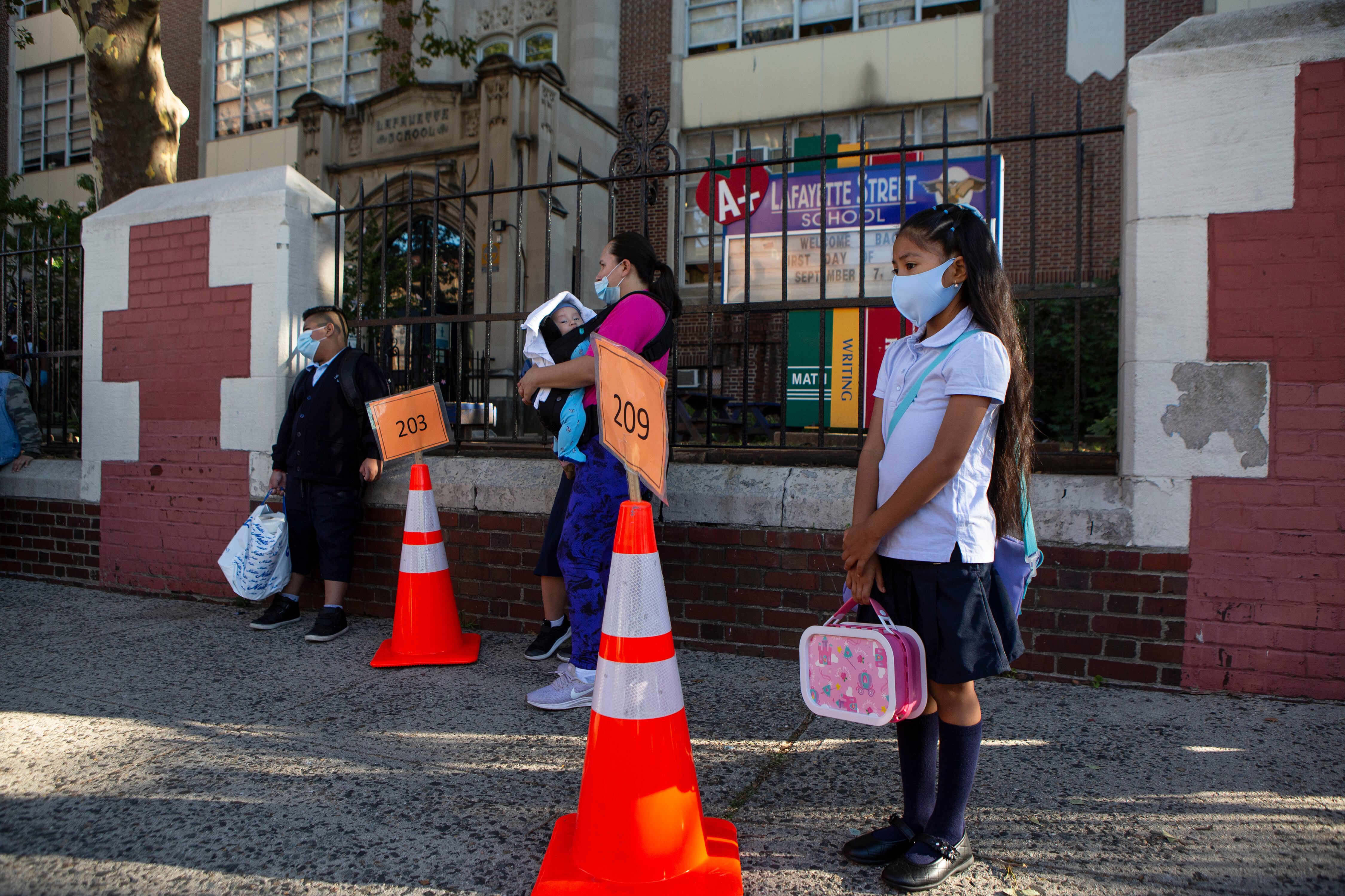 A girl waits at a large orange traffic cone on the first day of school at Newark’s Lafayette Street School.
