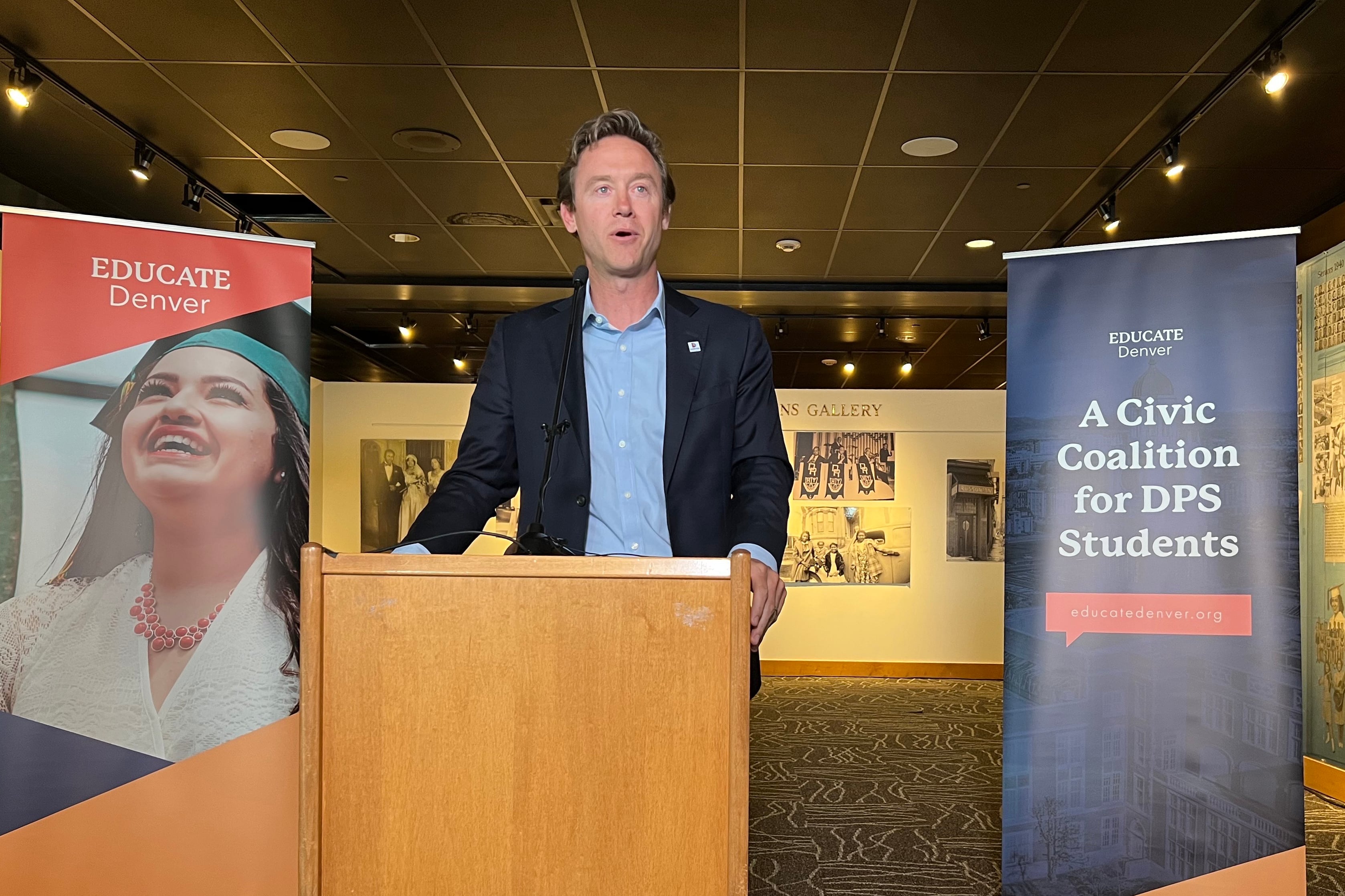 Denver Mayor Mike Johnston speaks at a podium.