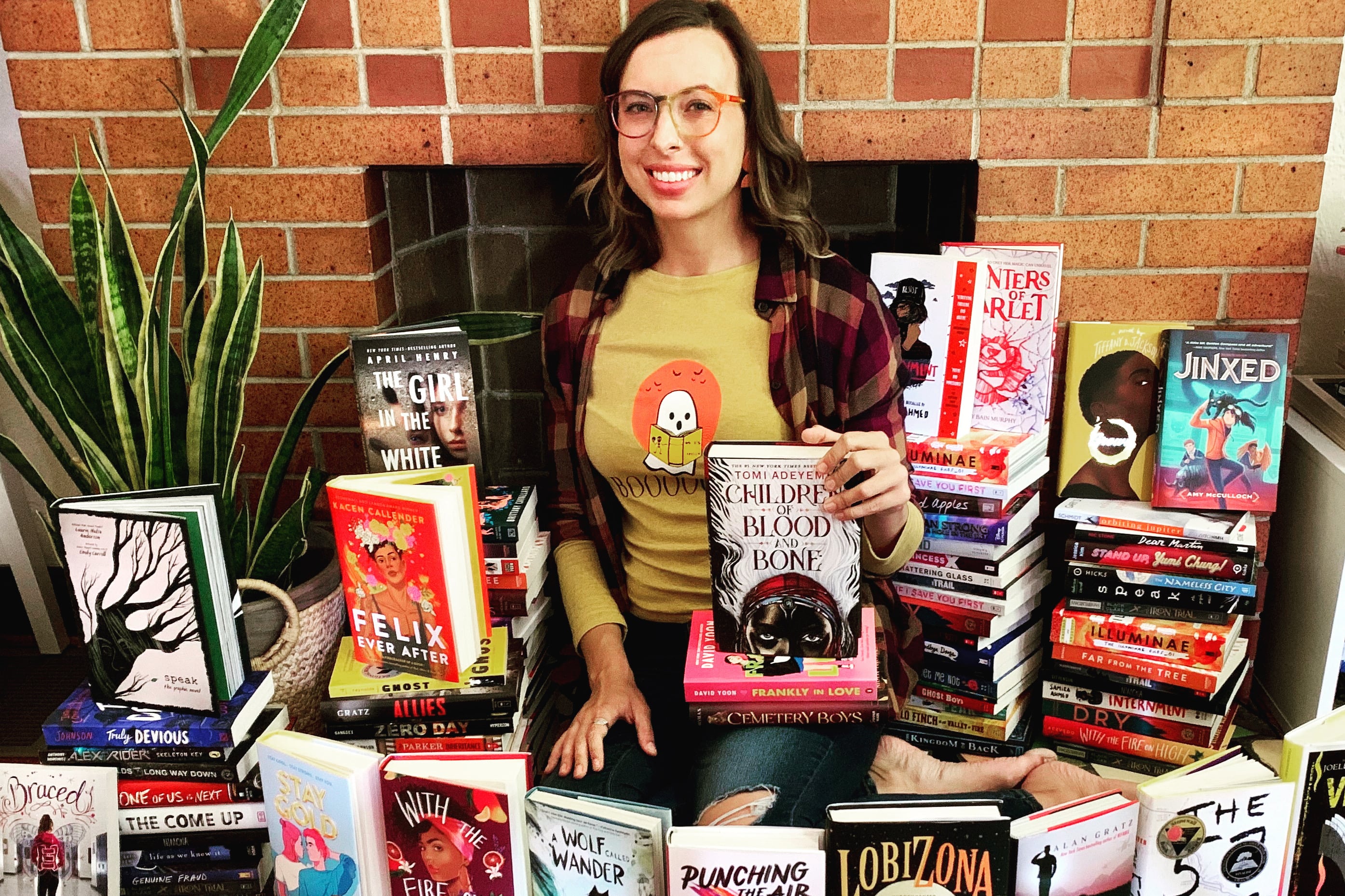 Woman stands amid a bunch of middle grade and YA novels.