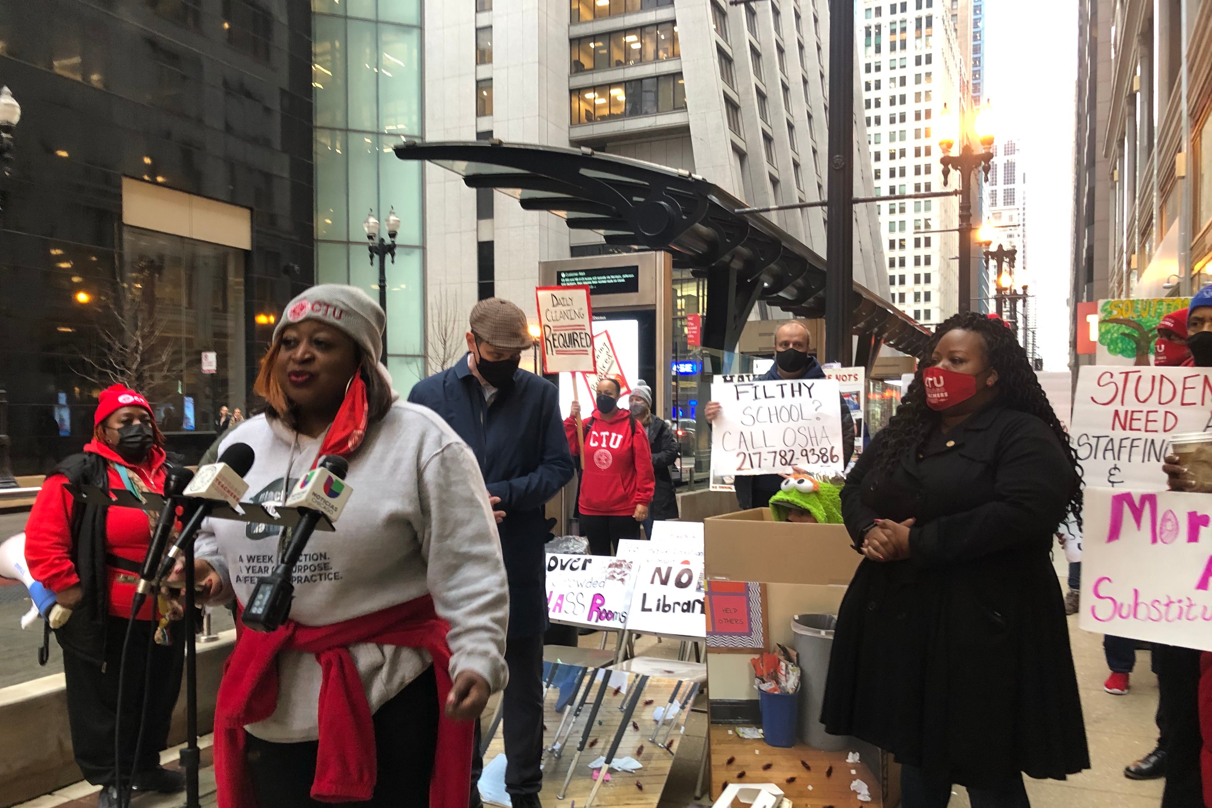 A woman at a microphone stand surrounded by members of the Chicago Teachers Union.